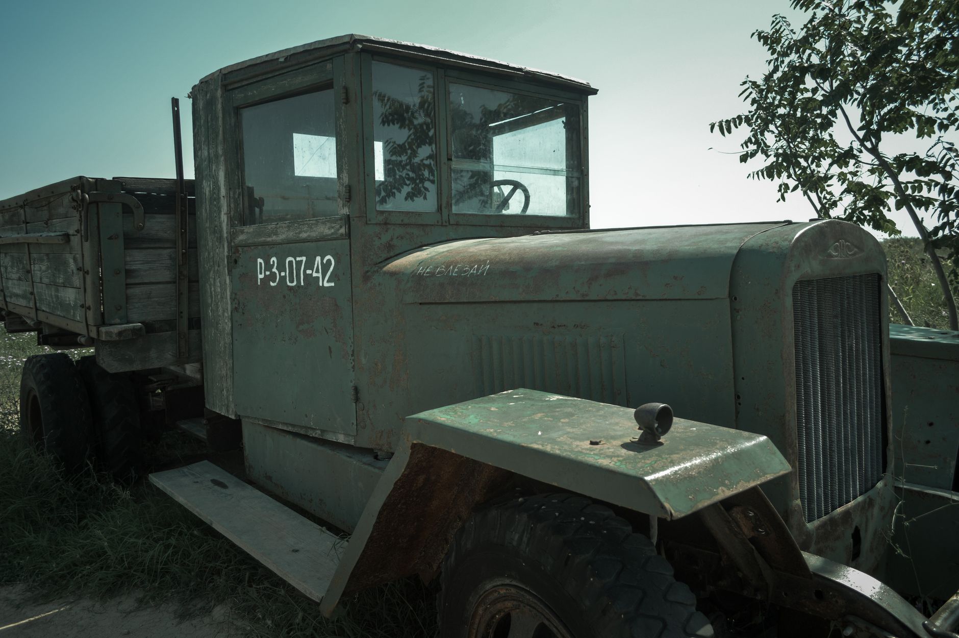 An old, rusted military truck parked in a field, showing signs of decay.