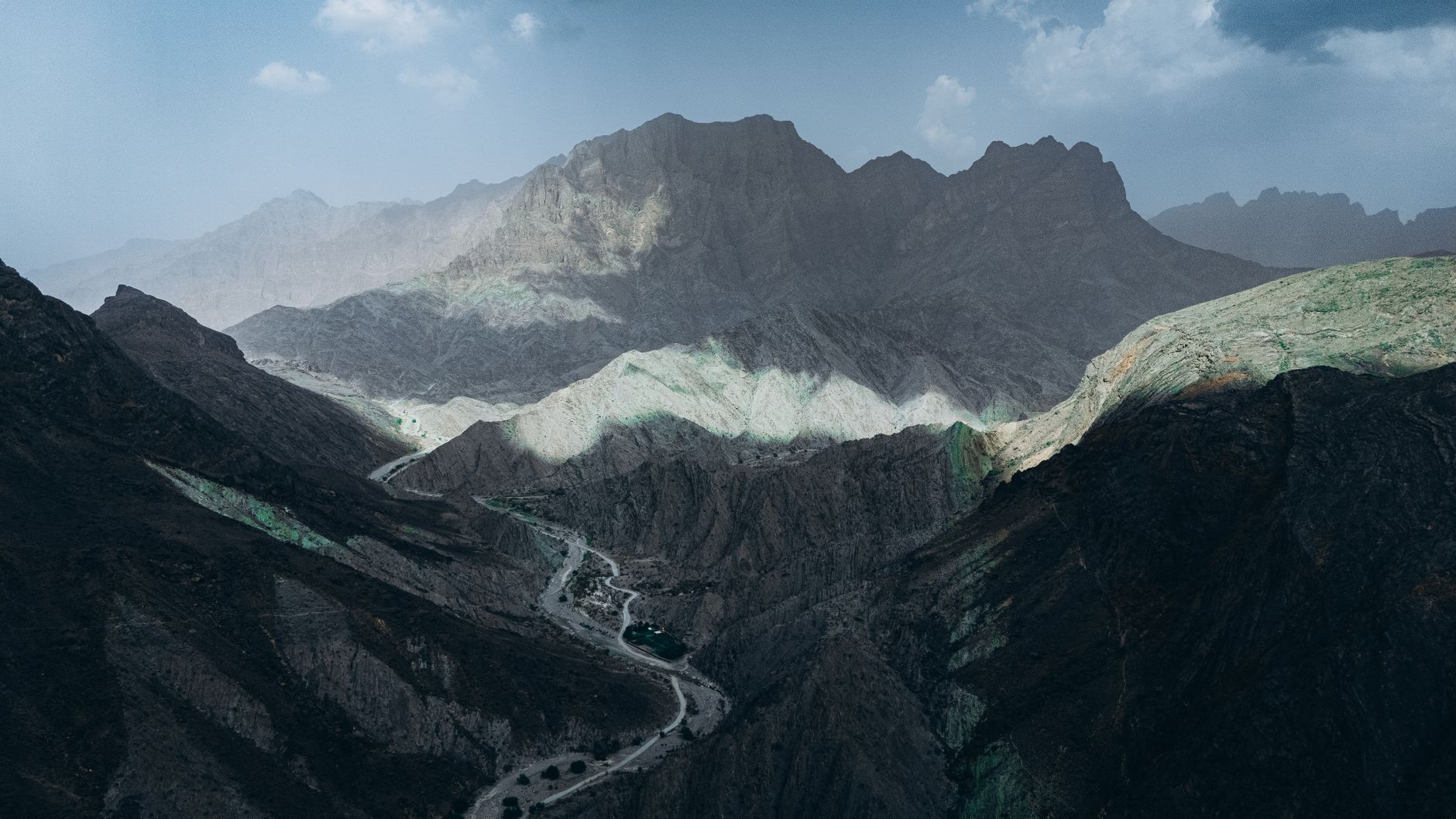 Stunning aerial view of the dramatic Oman mountains under a clear blue sky, showcasing nature's grandeur.