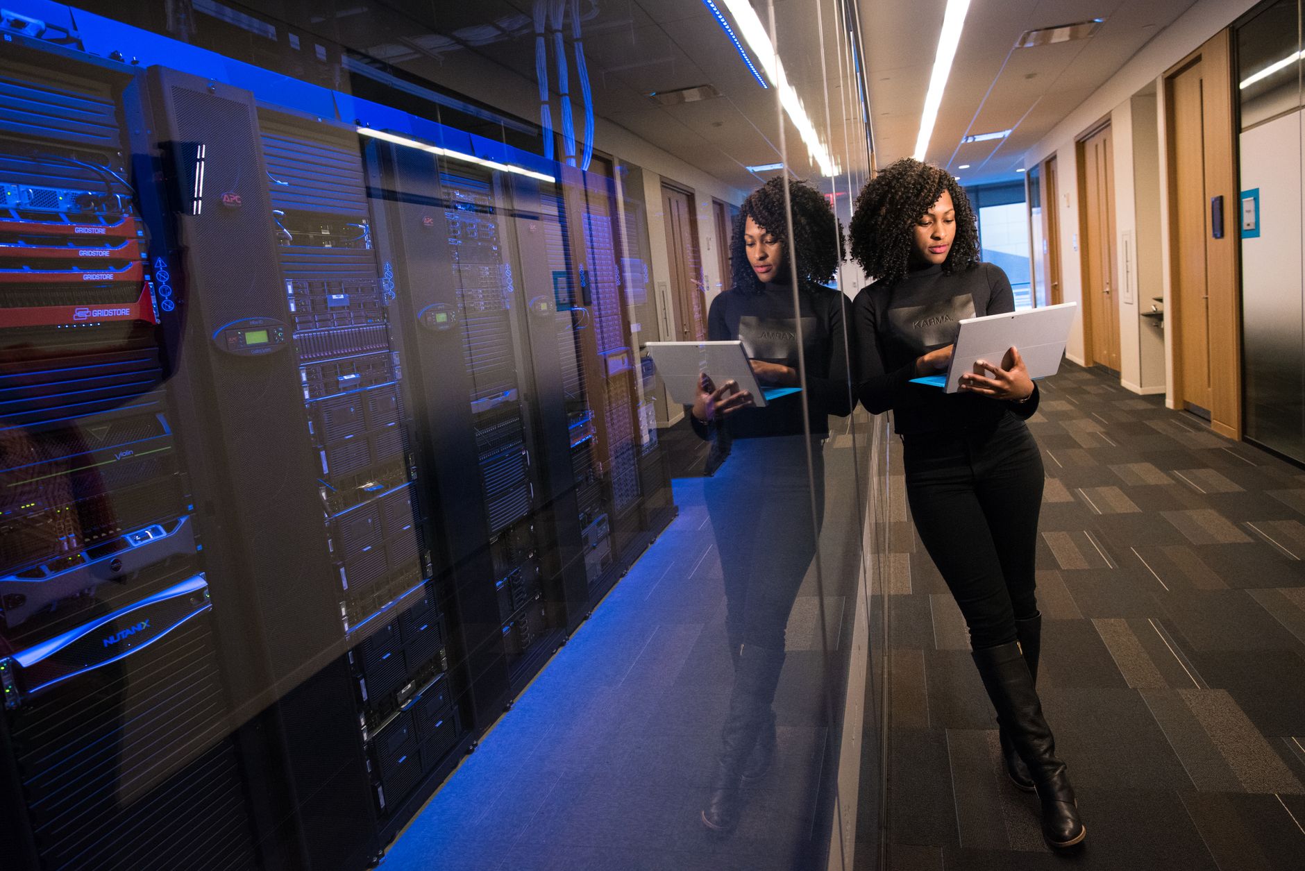 A woman using a laptop navigating a contemporary data center with mirrored