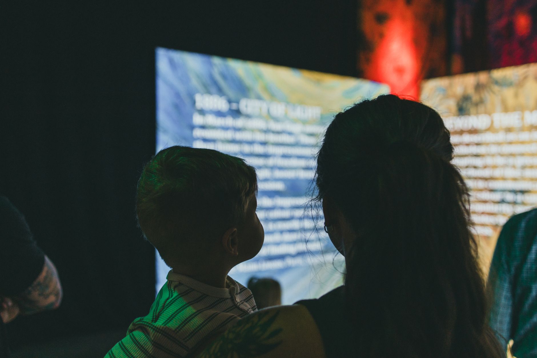 Silhouettes of a woman and child observing digital art and text on