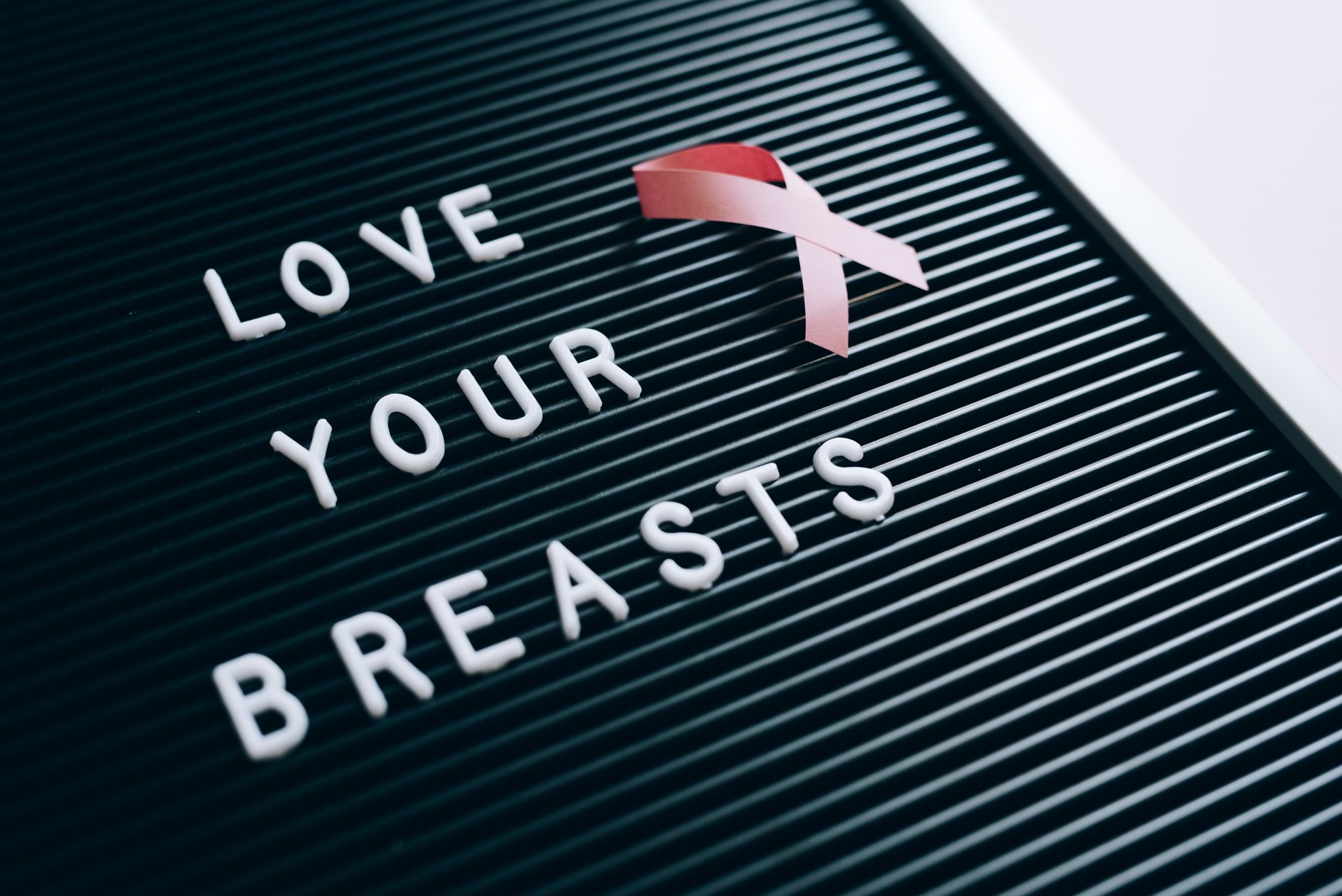 Close-up of a letter board with 'Love Your Breasts' message and pink