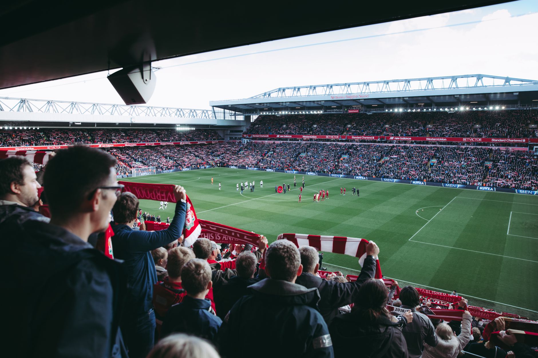Fans cheer as players take the field at a vibrant football stadium,