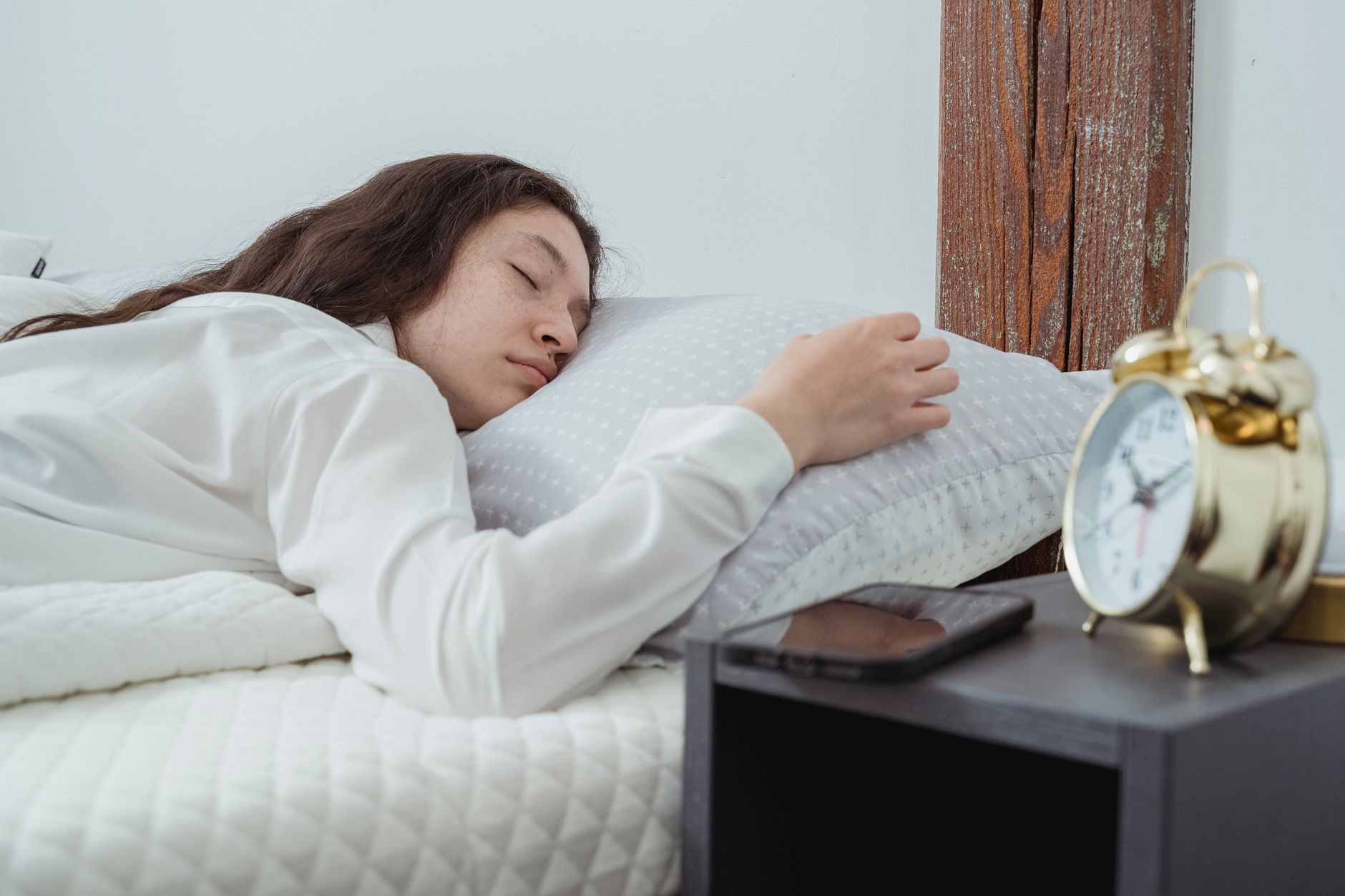 Young woman with dark long wavy hair sleeping peacefully on belly on