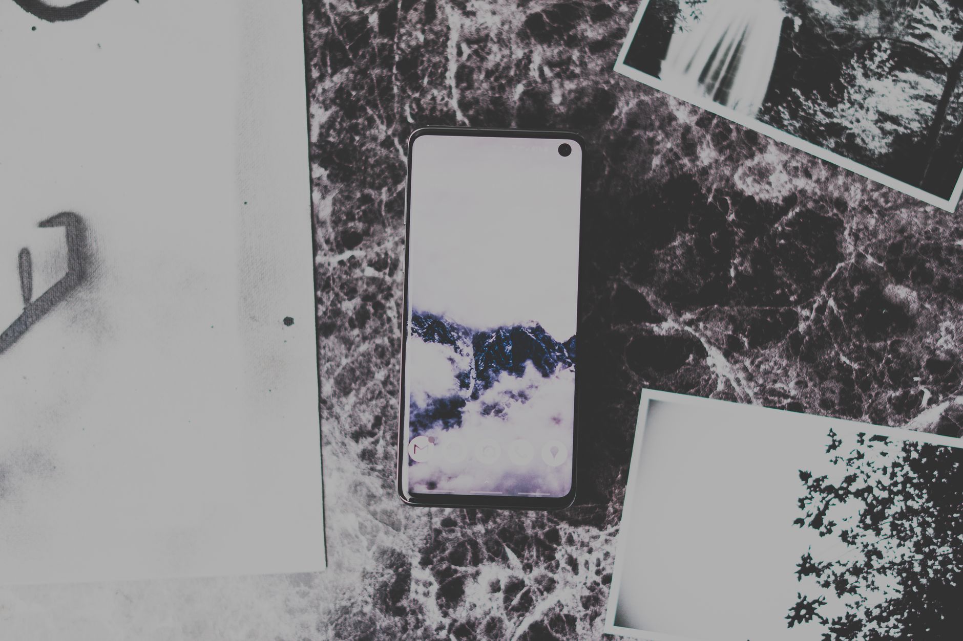 Flat lay of a smartphone on marble surface surrounded by black and