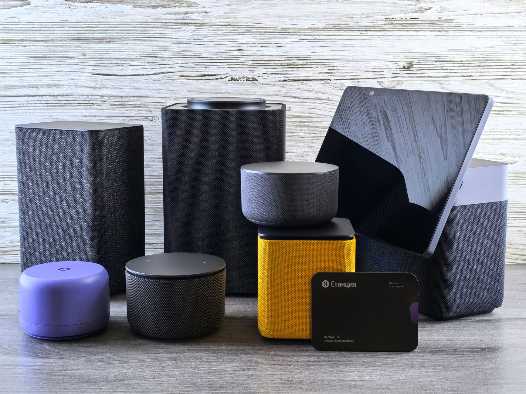 A collection of various smart home speakers and tablet displayed on a