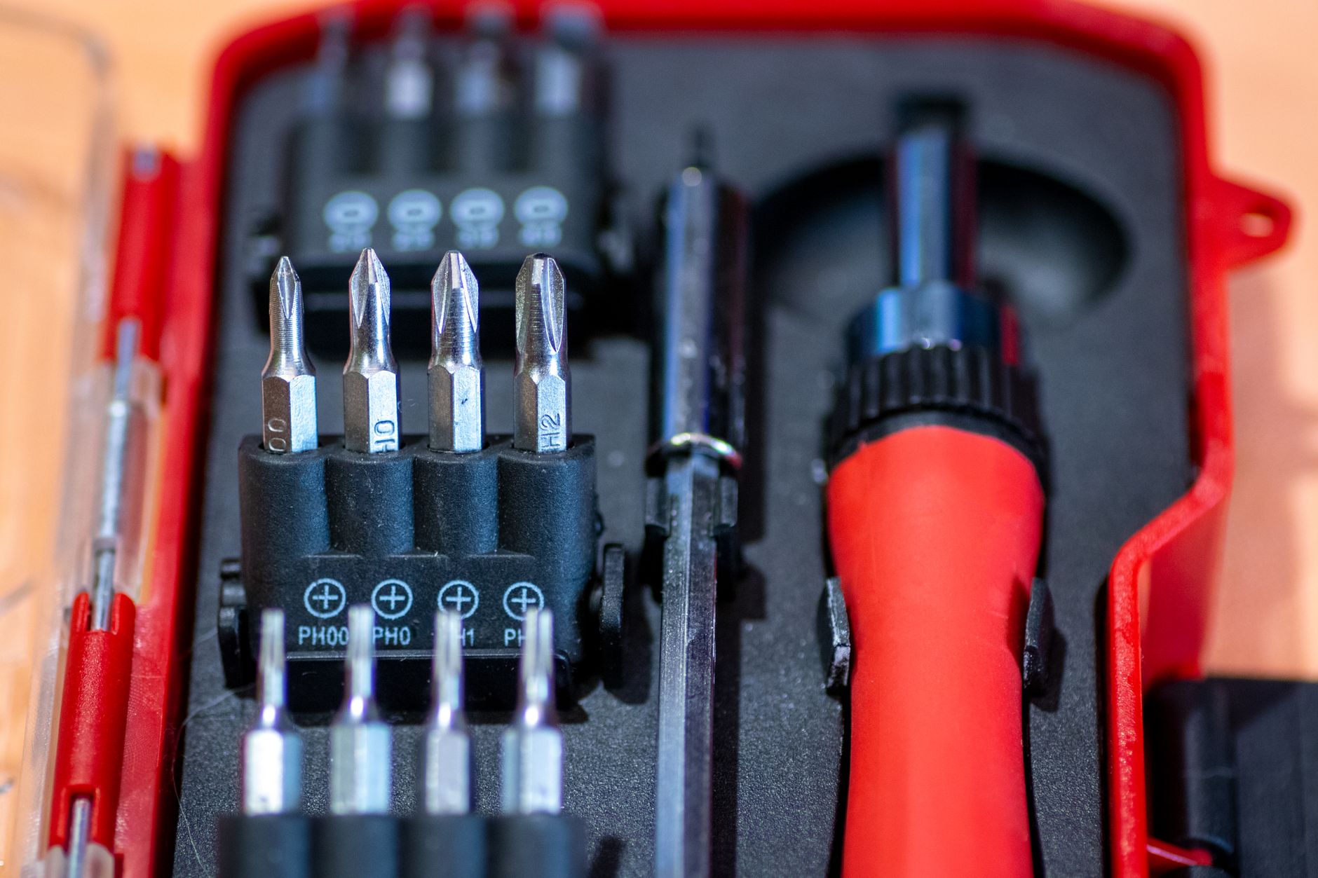 Detailed view of a screwdriver set in a red case, featuring interchangeable bits and tools.