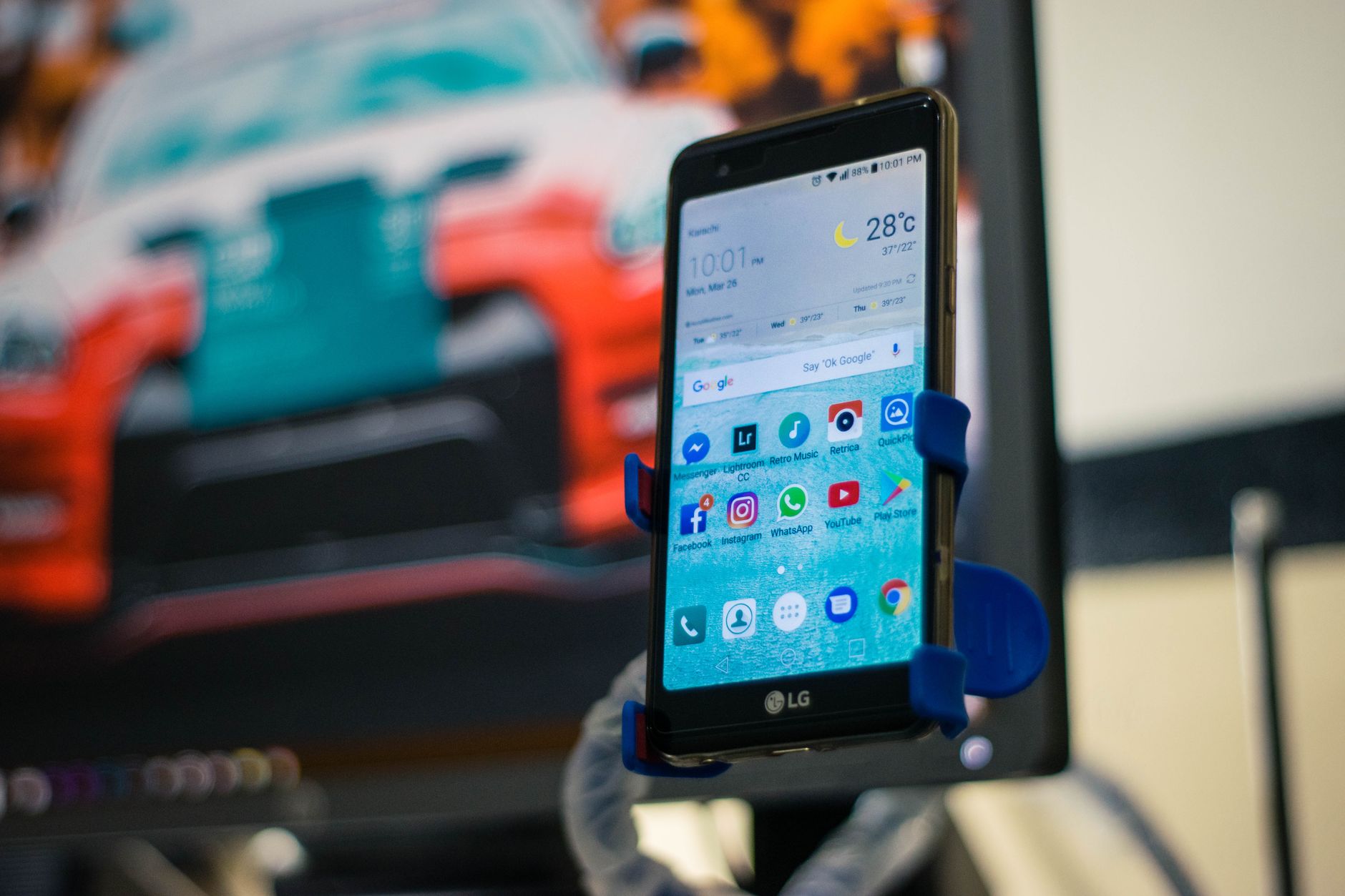 LG smartphone securely mounted in a car holder indoors, displaying various apps