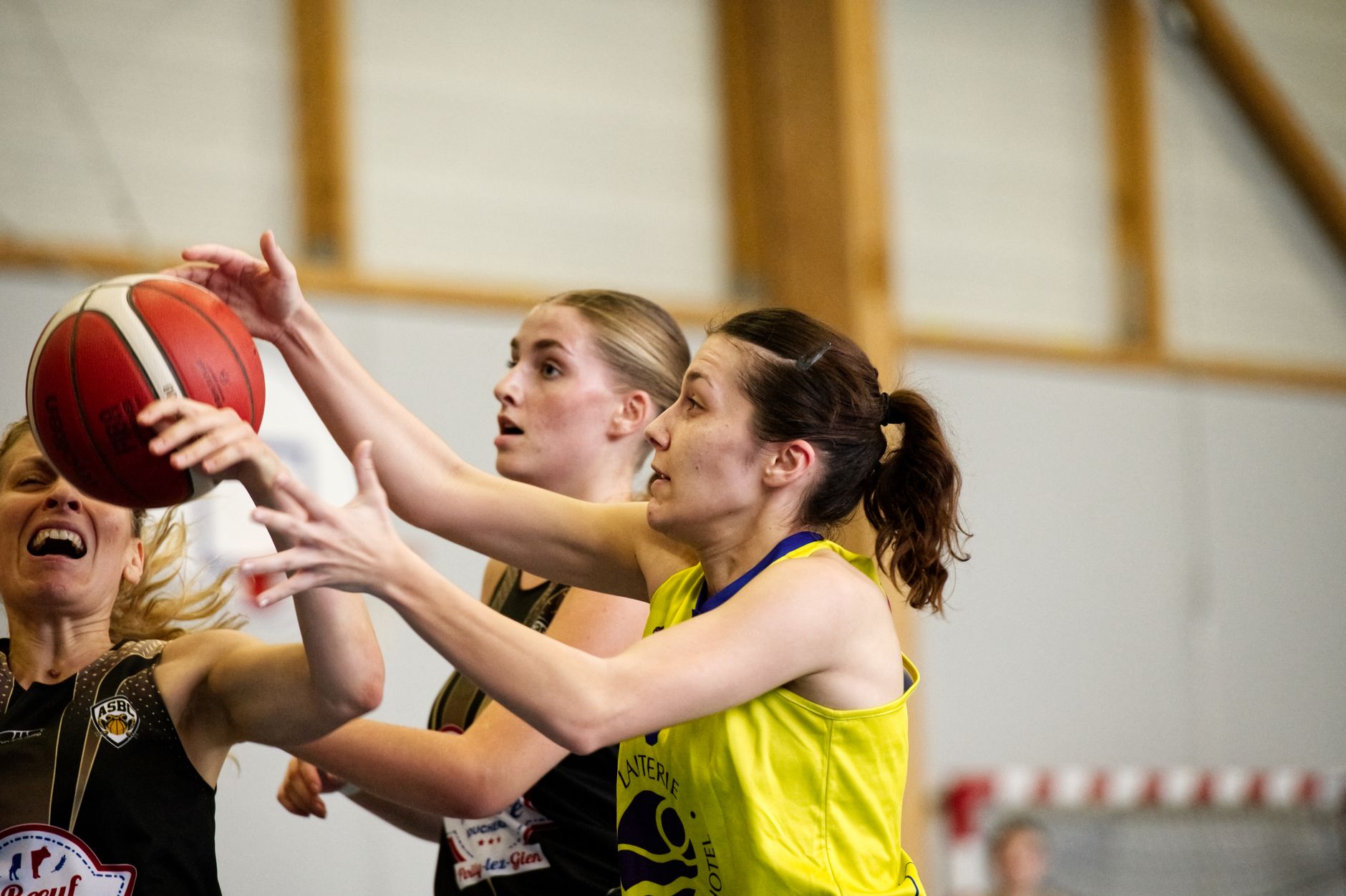 Close-up of women basketball players in a competitive game, reaching for a
