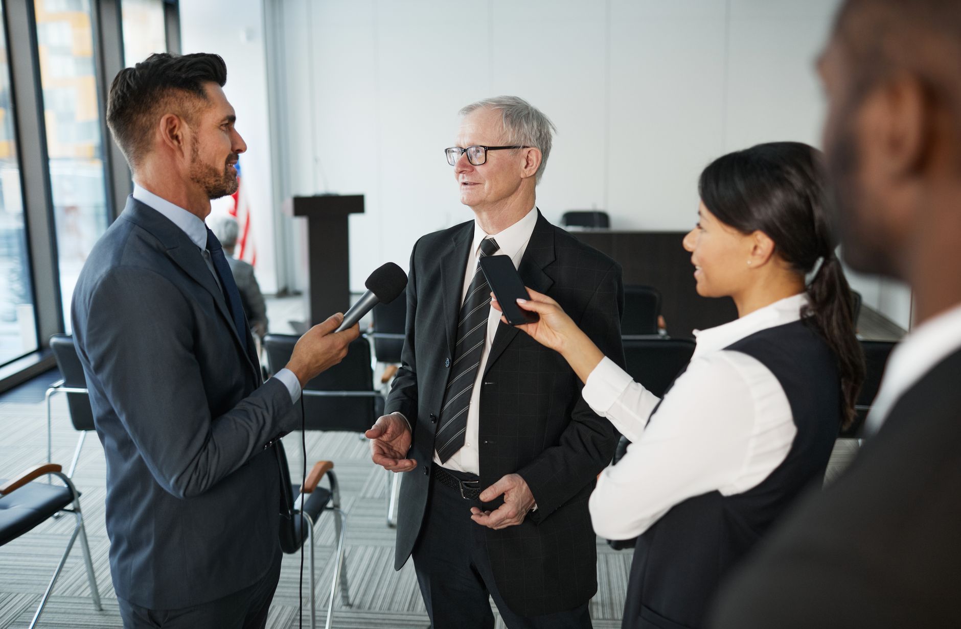 Journalists conduct an interview with a senior executive in a formal office