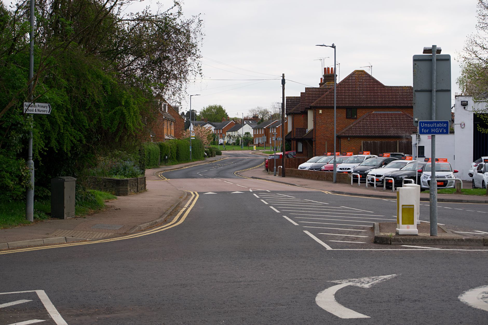 Serene suburban street in England, showcasing residential houses and road signs on