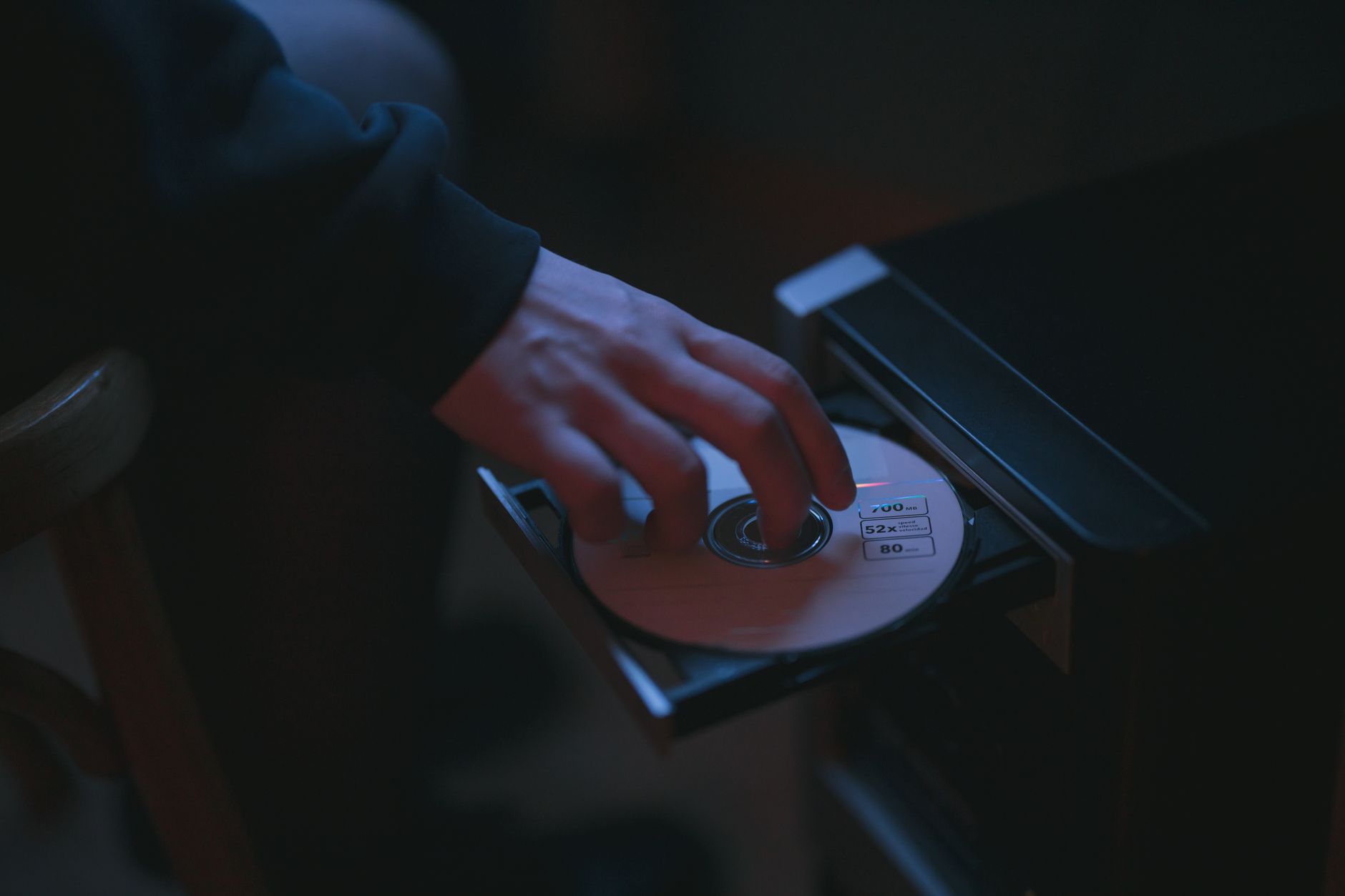 A hand inserting a CD into a computer drive, highlighting cyber security