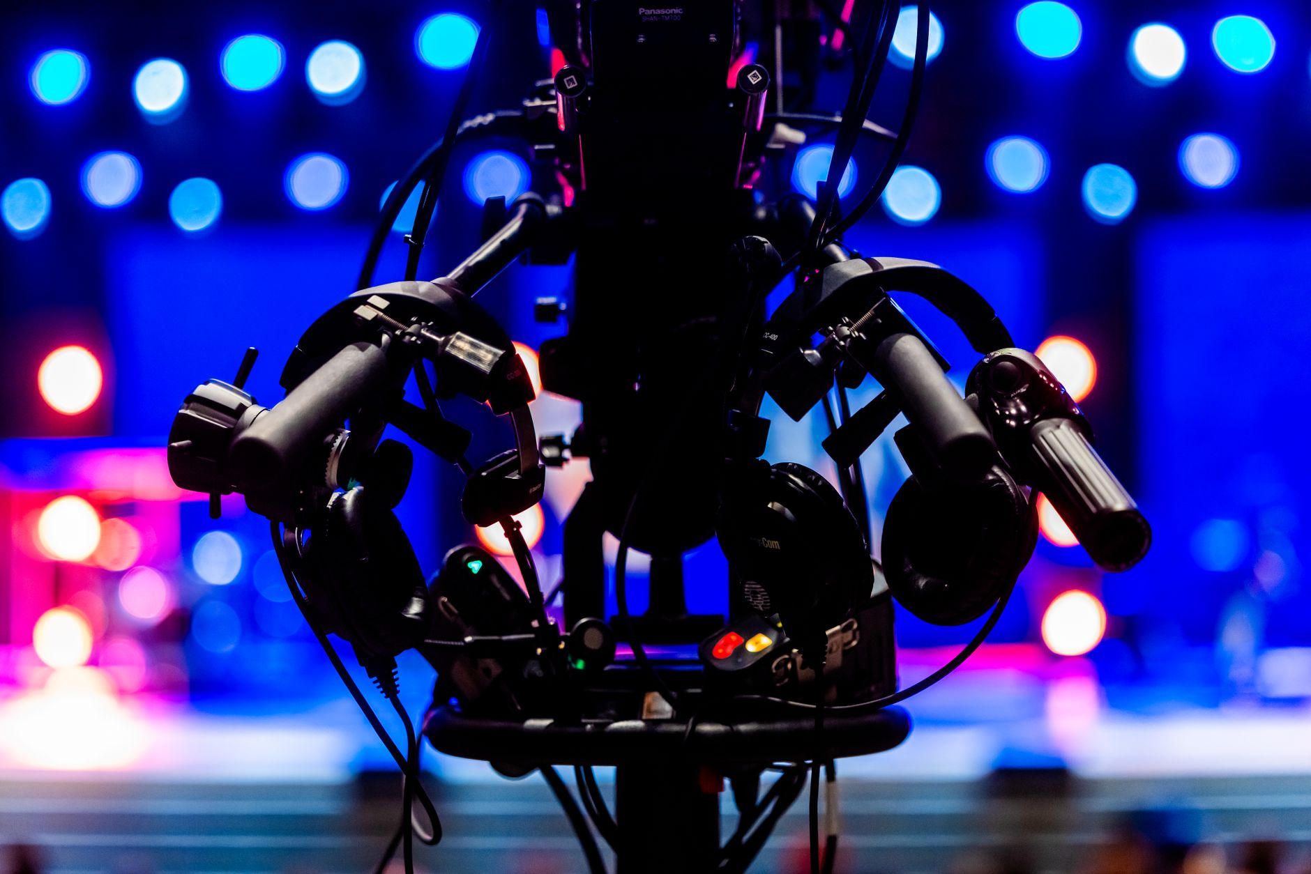 Silhouette of a professional video camera with colorful stage lights in the