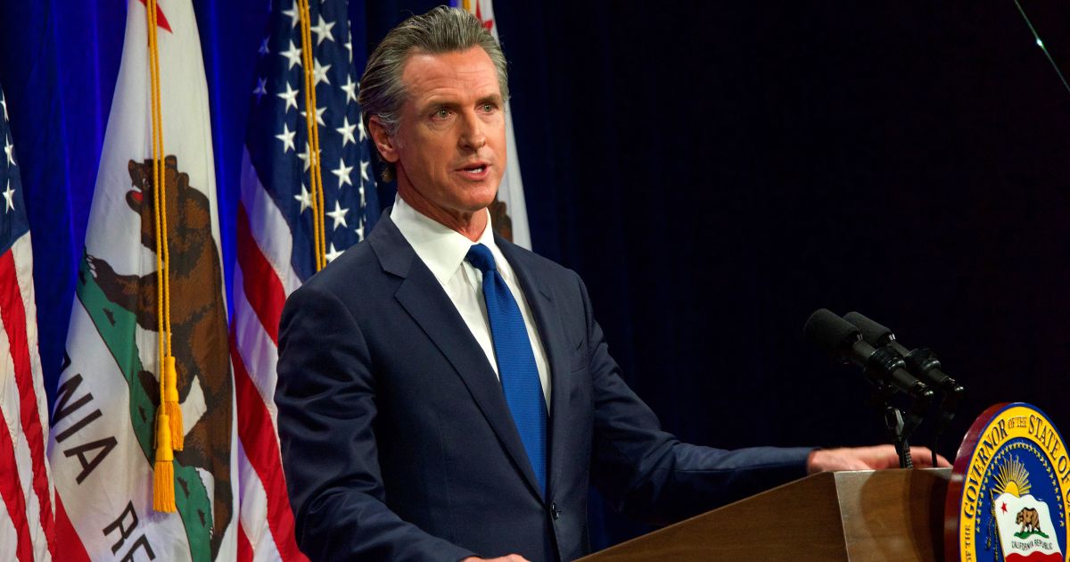 California Gov. Gavin Newsom speaks at a podium in front of California and U.S. flags during the child marriage ban bill signing.