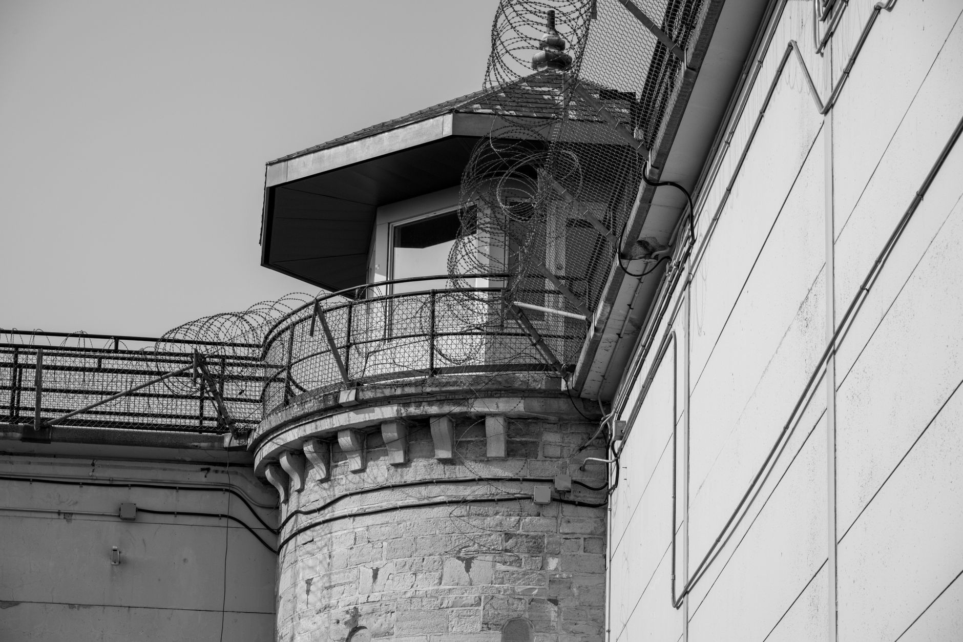 Black and white image of a prison tower secured with barbed wire
