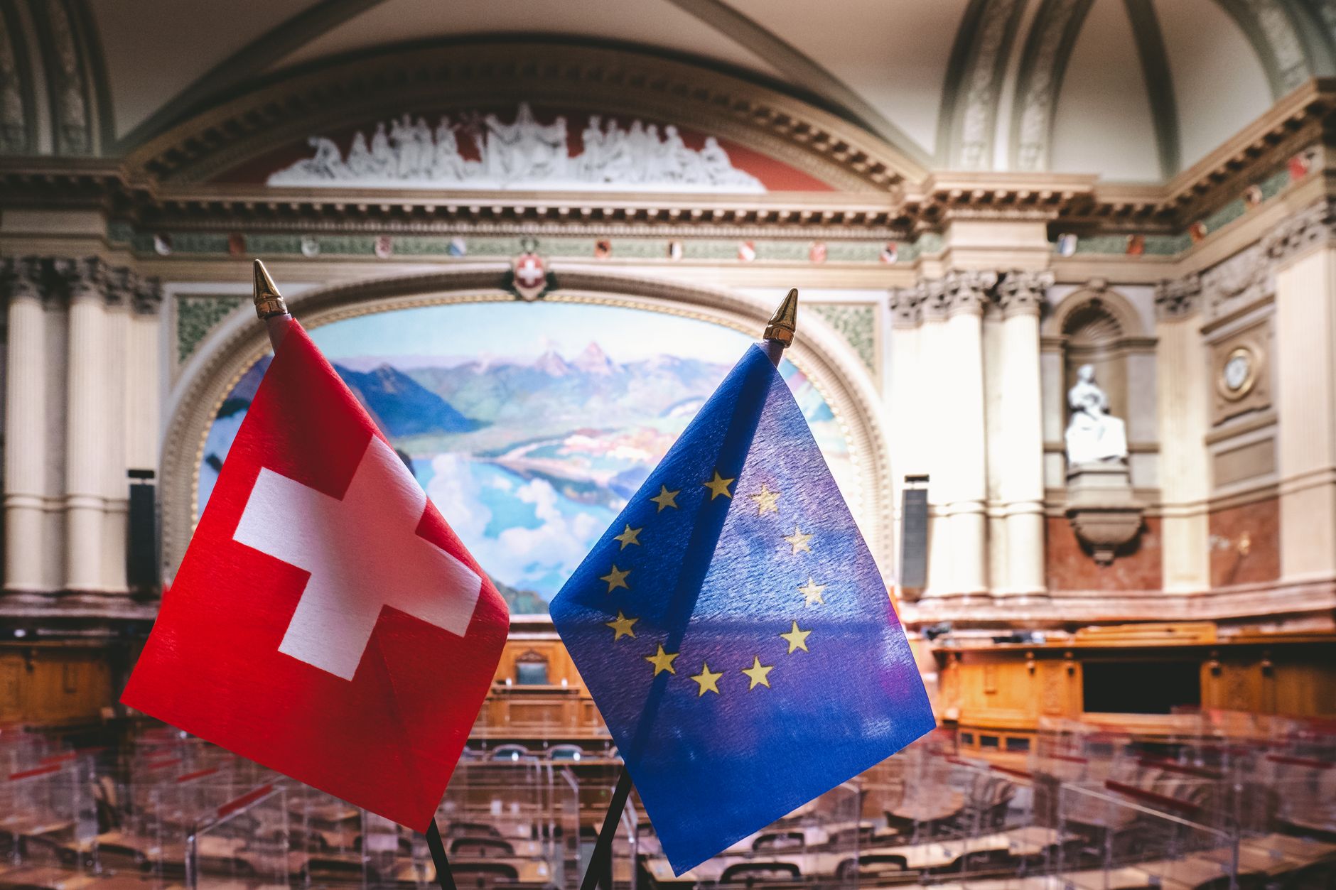 Swiss and EU flags inside the Swiss Parliament building in Bern, showcasing