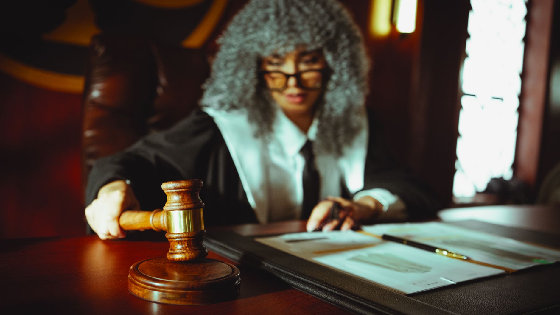 Female judge in a courtroom setting, focusing on legal documents with a