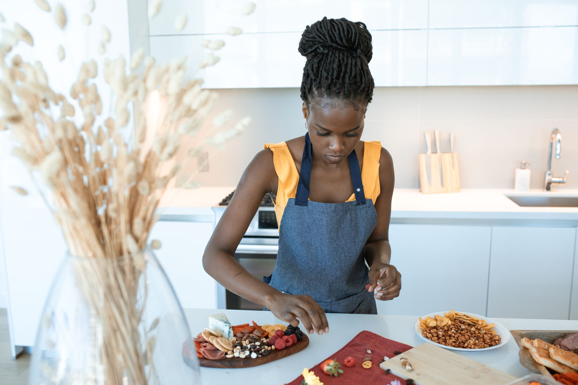 An adult woman arranges a colorful charcuterie board on a kitchen counter