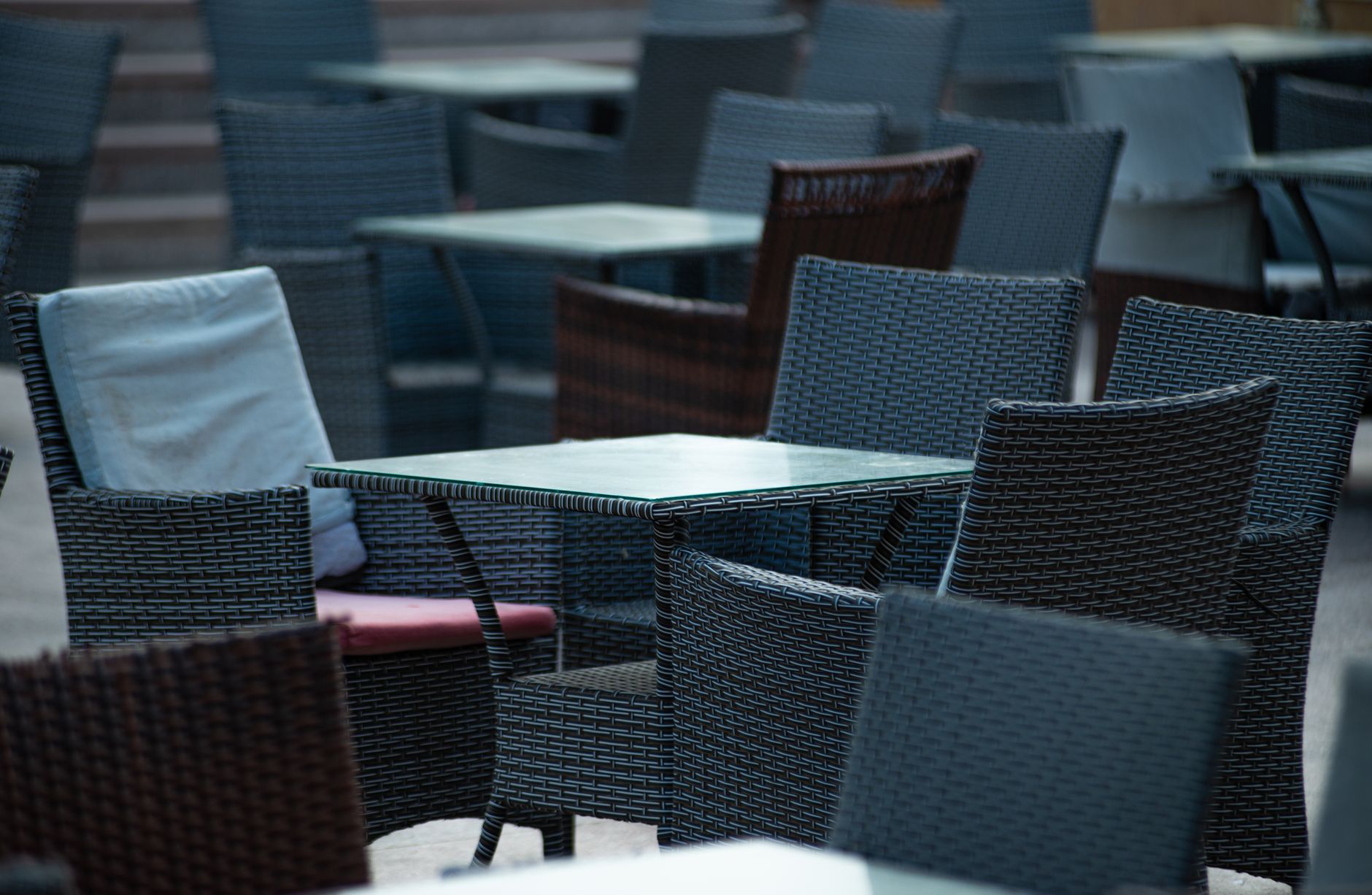 Empty outdoor terrace with wicker chairs and tables, creating a cozy café