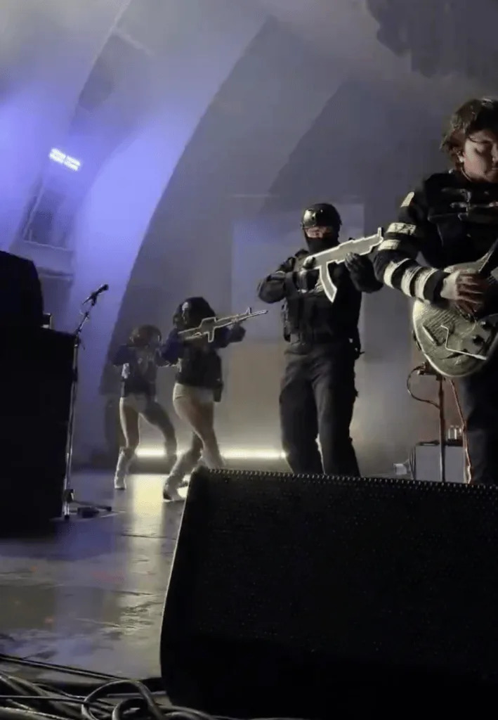 My Chemical Romance performs in concert with women dressed in cheerleader uniforms
