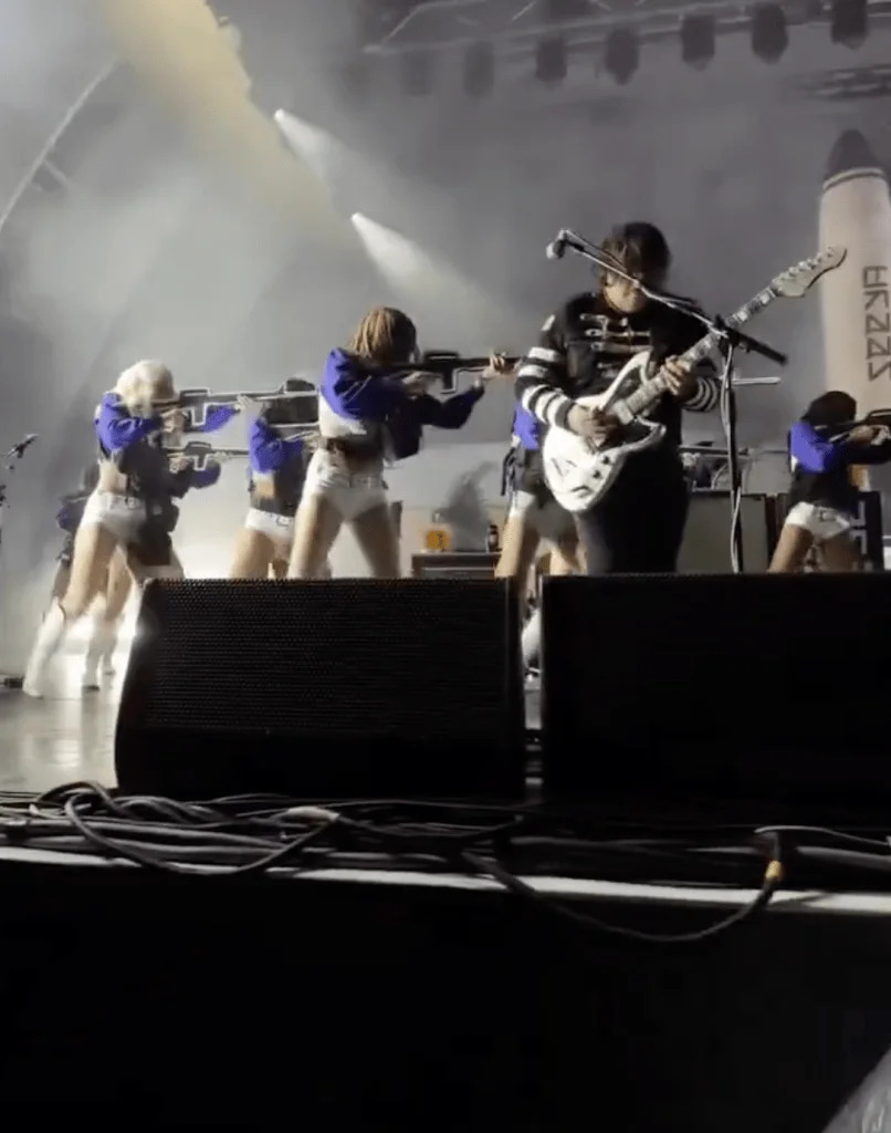 Women dressed in white and blue cheerleader costumes perform on stage during a My Chemical Romance concert at the Hollywood Bowl.