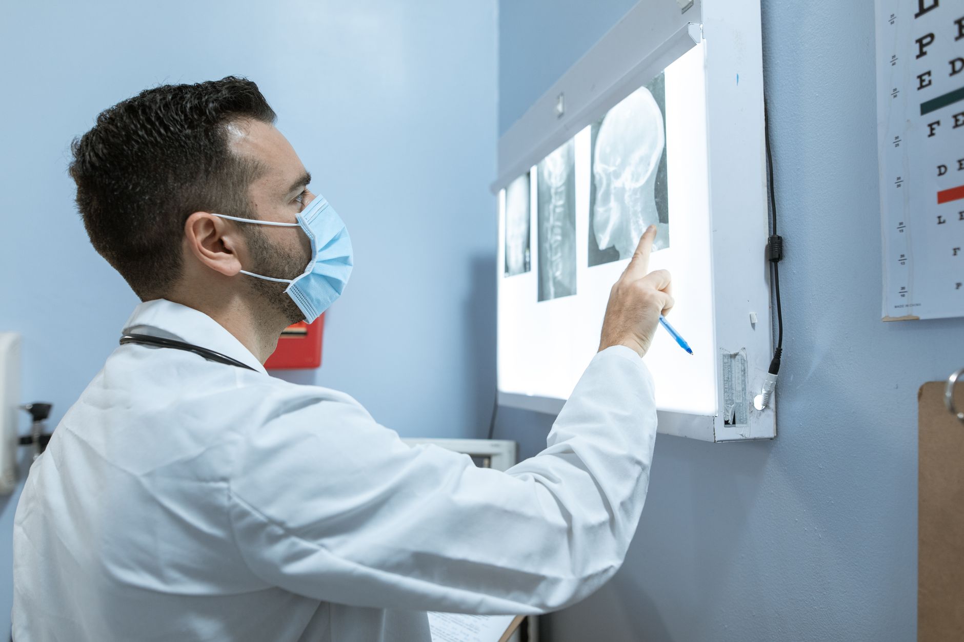 A healthcare professional examines brain X-rays while wearing a face mask in