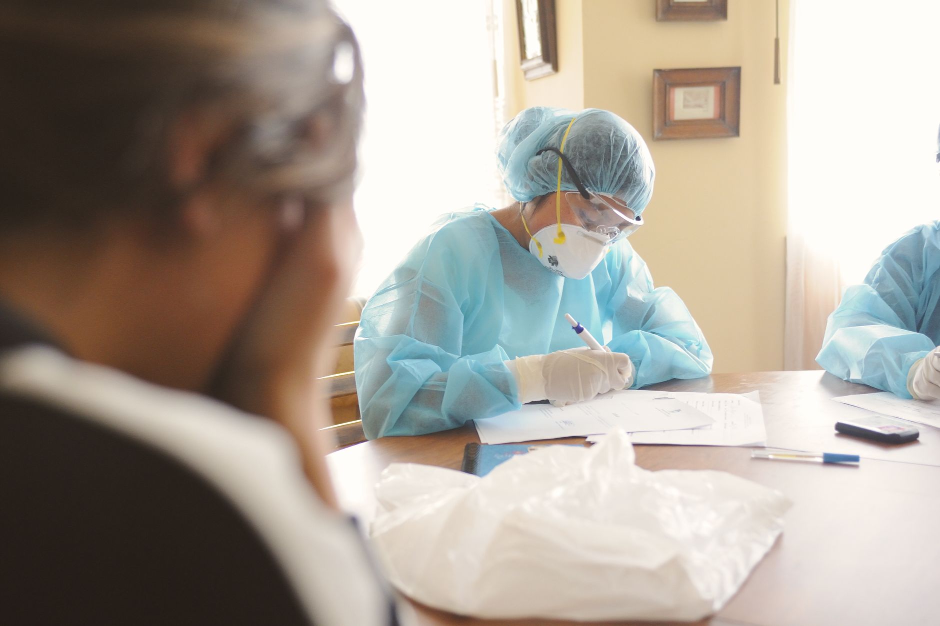 Medical professionals in PPE working at a desk during a daytime setting
