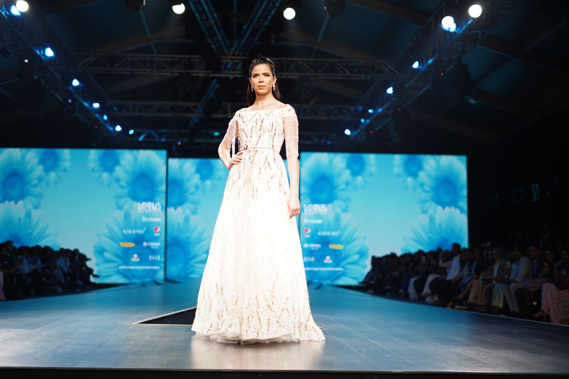 Model showcasing an elegant white dress on the runway during a high-fashion