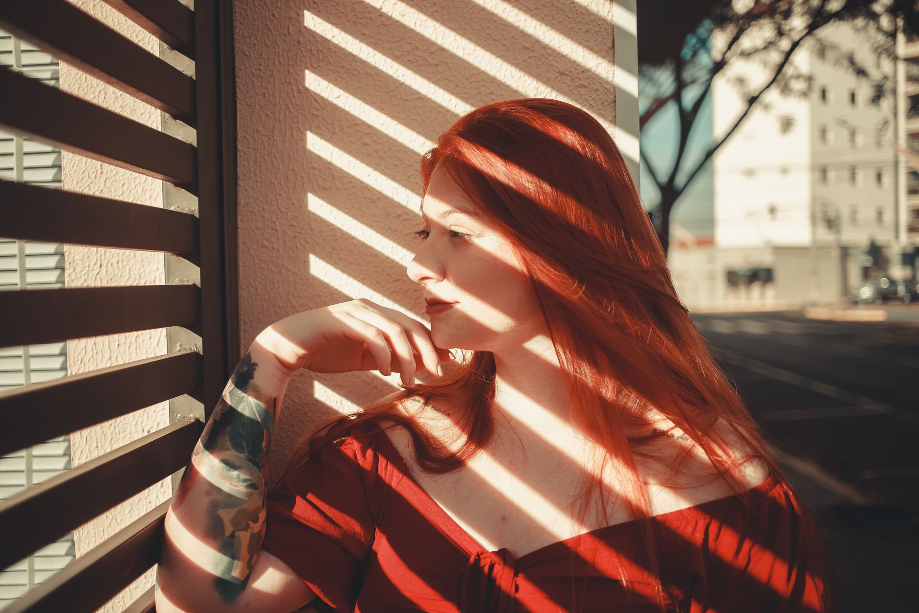 Elegant woman with red hair posing indoors with striking light and shadow