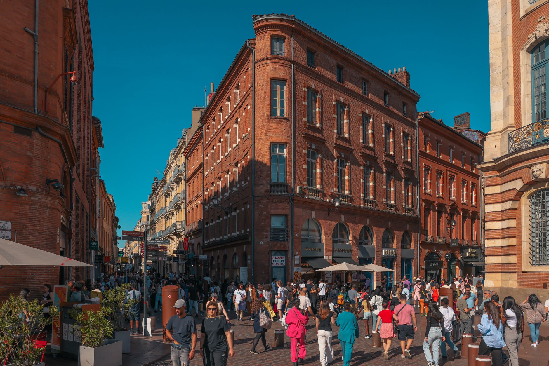 Vibrant street scene in Toulouse's historic district with crowds and red brick