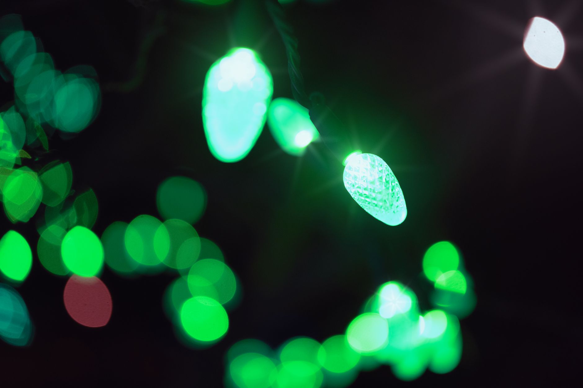 Close-up of glowing green LED lights with bokeh effect, creating a festive and vibrant atmosphere.