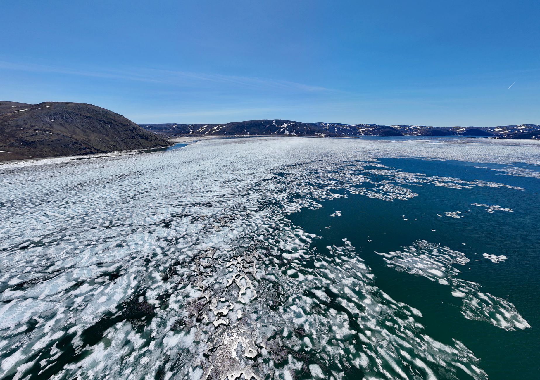 Aerial shot of an icy Arctic landscape with scattered ice floes under