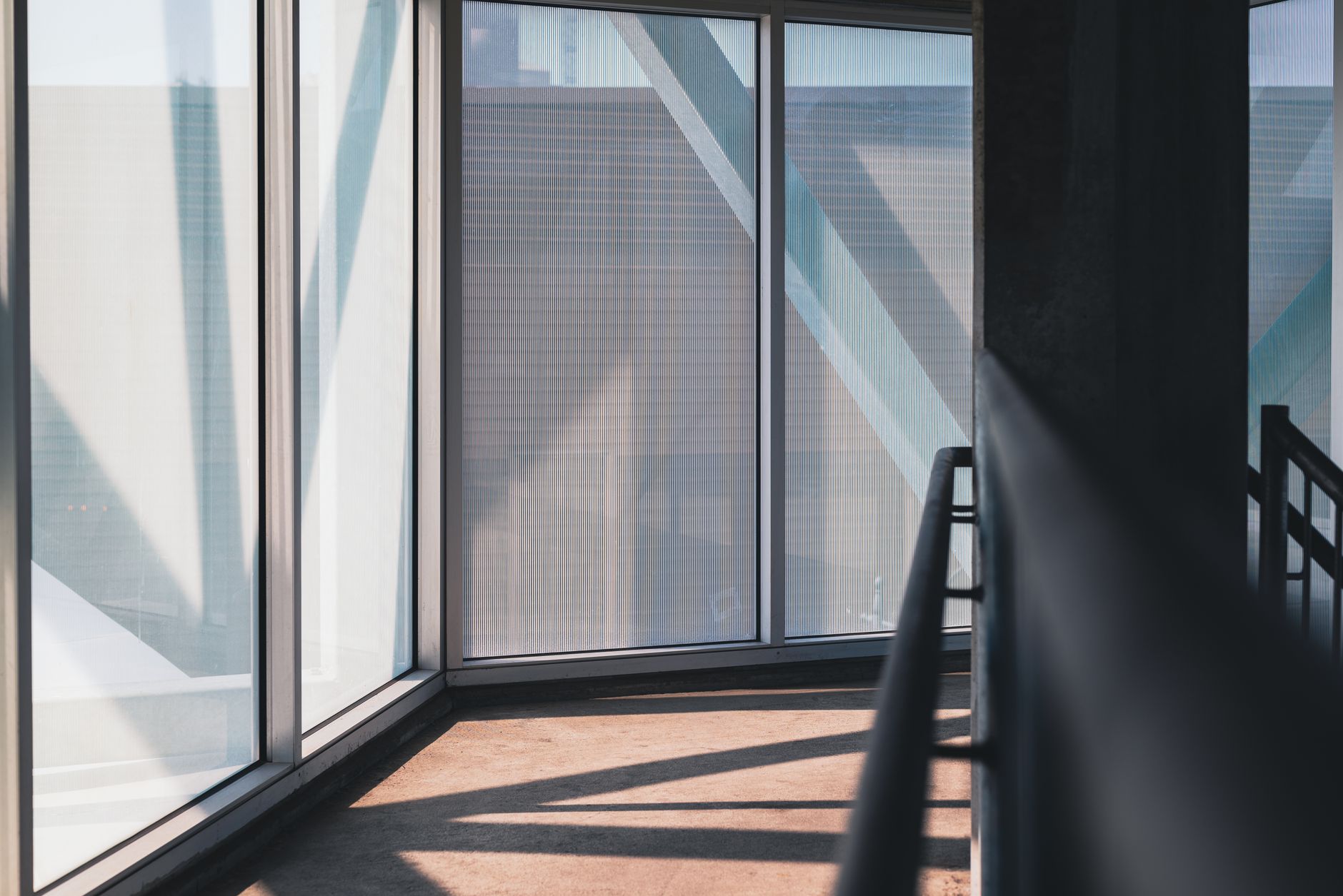 Sunlit modern corridor with large windows and metal railings offers a serene