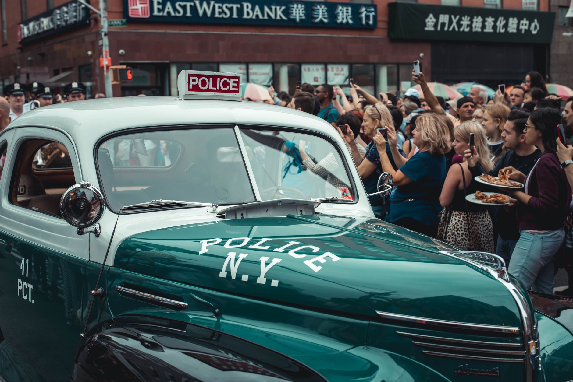 A classic NY police car surrounded by a crowd during a New
