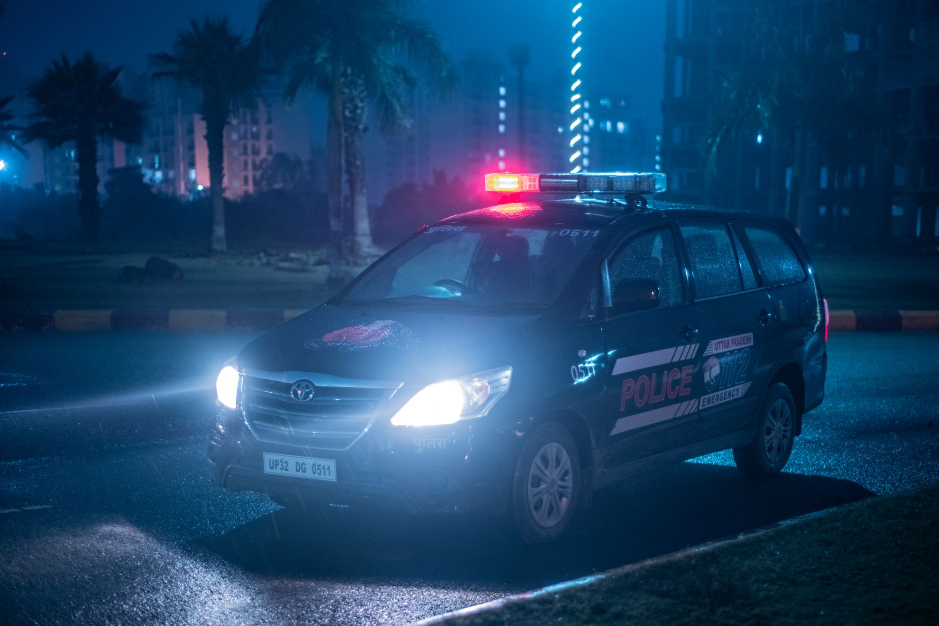 A Toyota police car patrols under city lights at night in Uttar Pradesh, India.