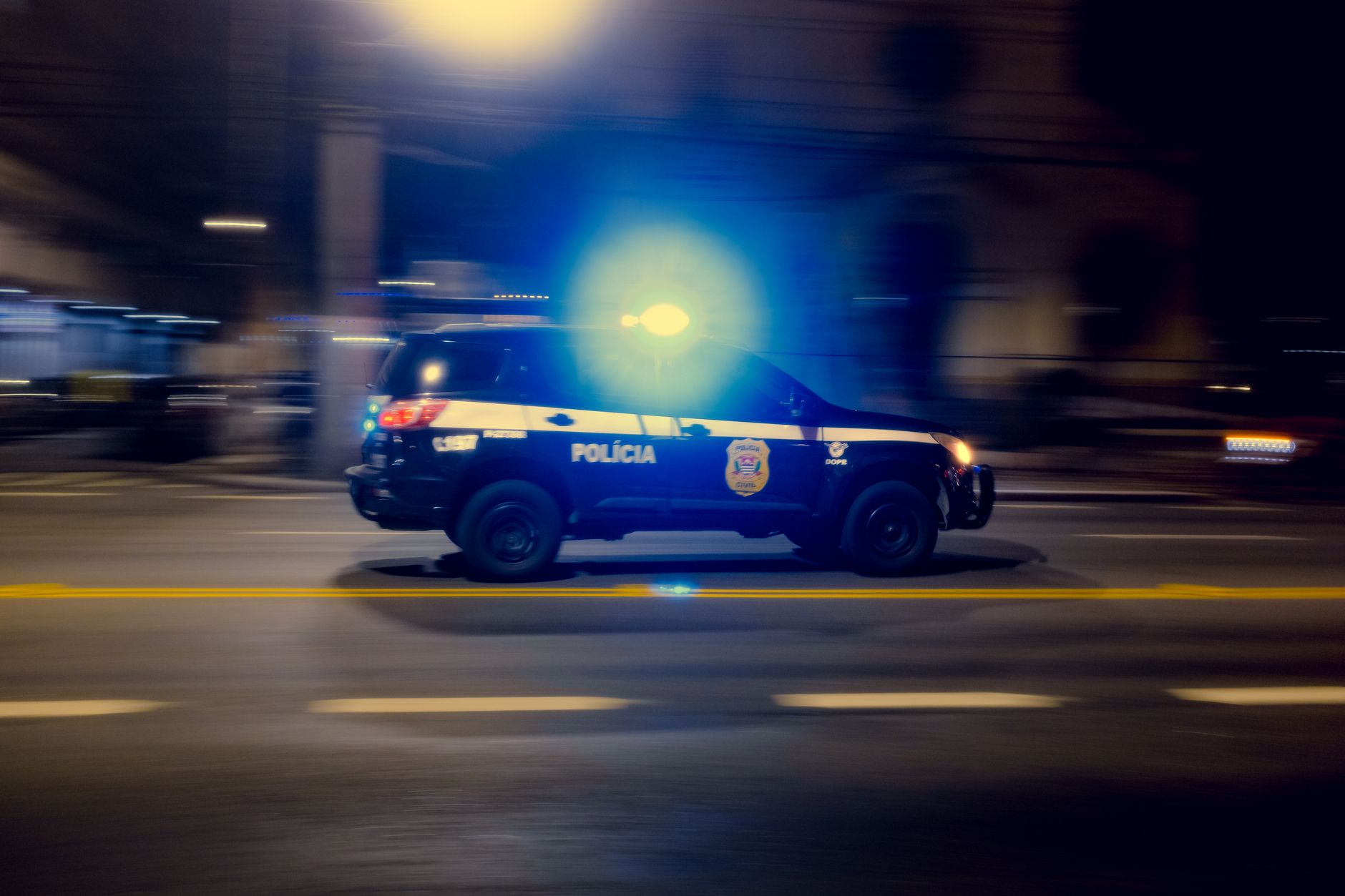 Blurred motion capture of a police car speeding at night with flashing