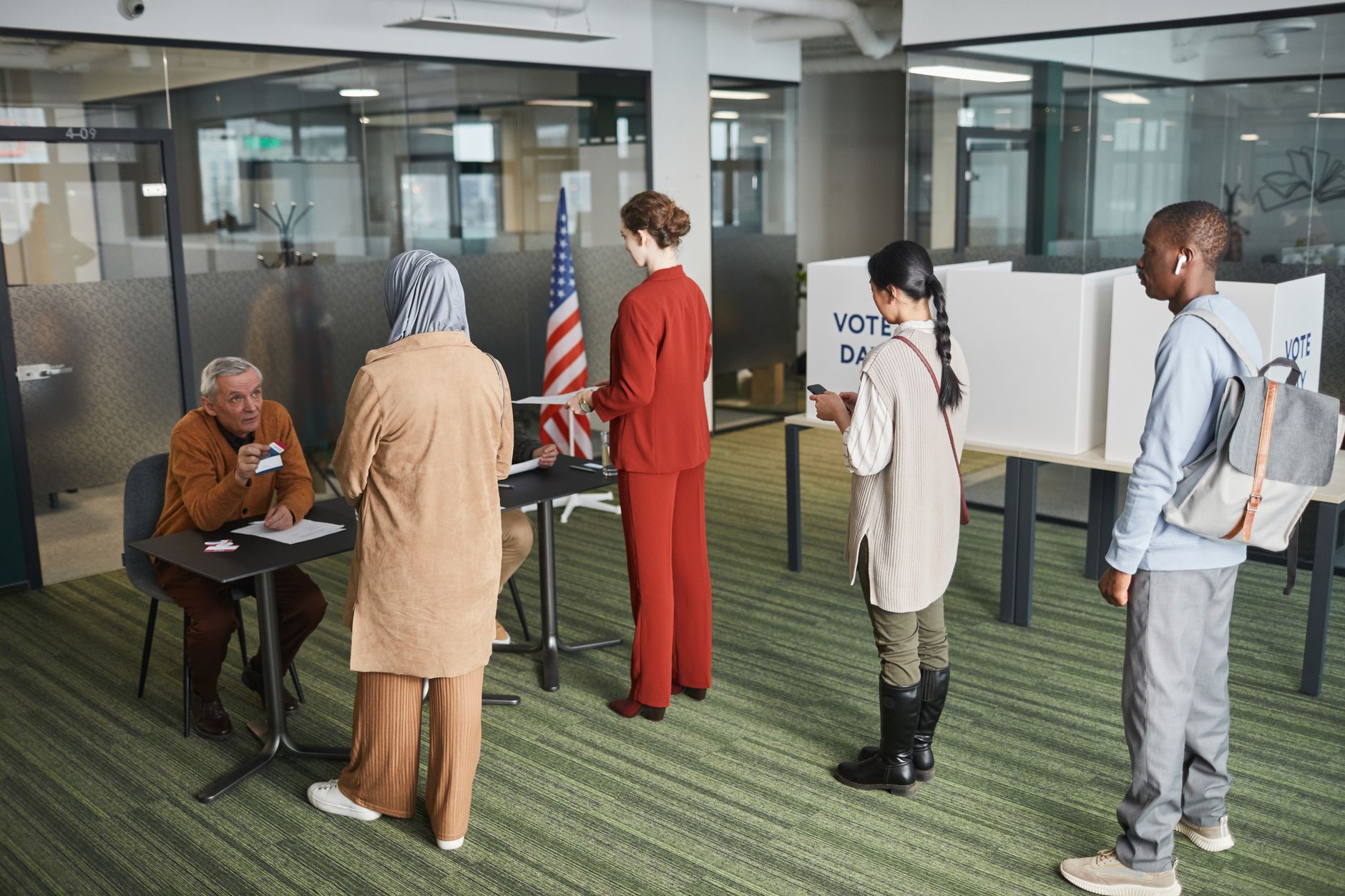 Diverse group of voters lining up at an indoor polling station on