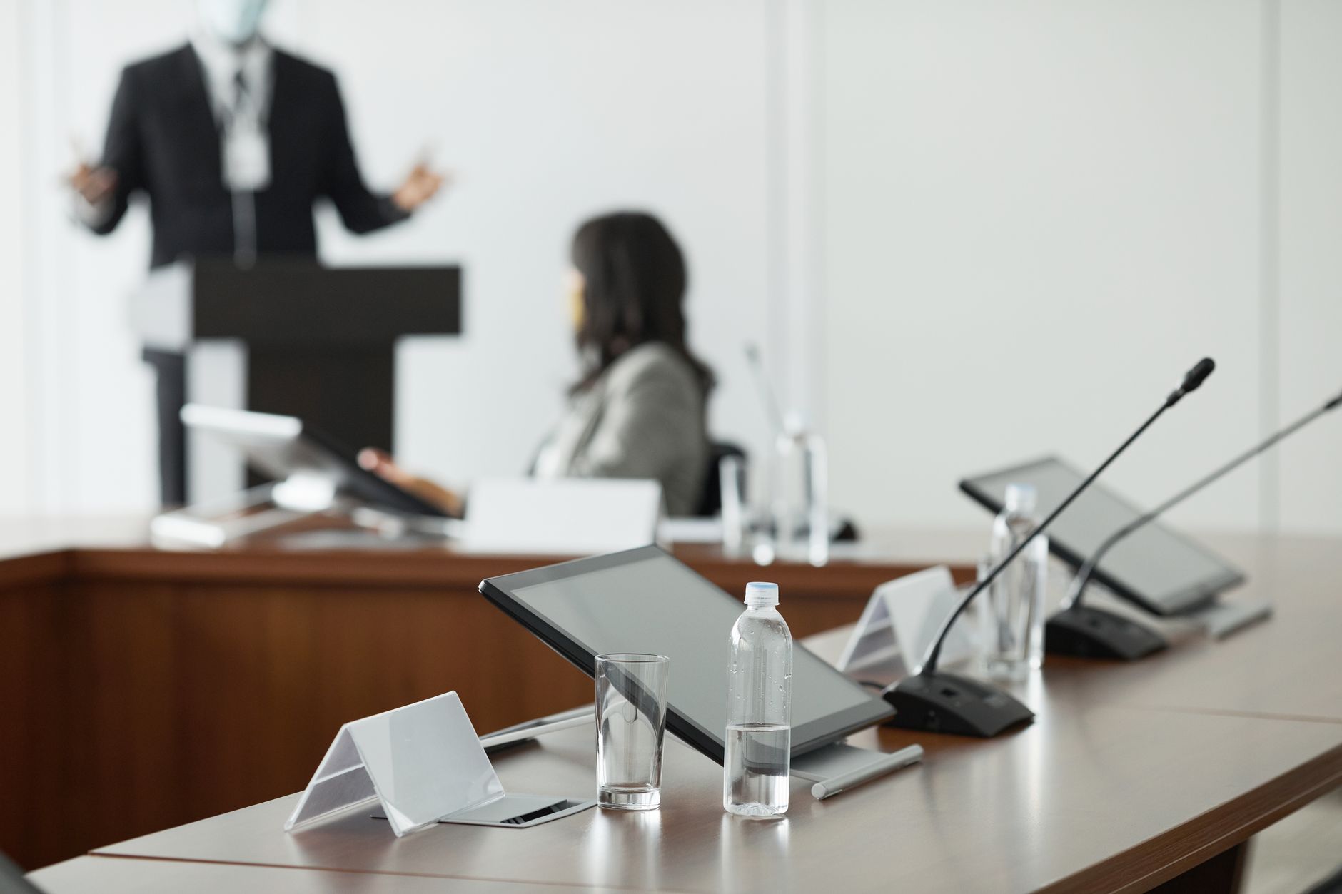 A conference room setup with tablets, microphones, and water bottles for a