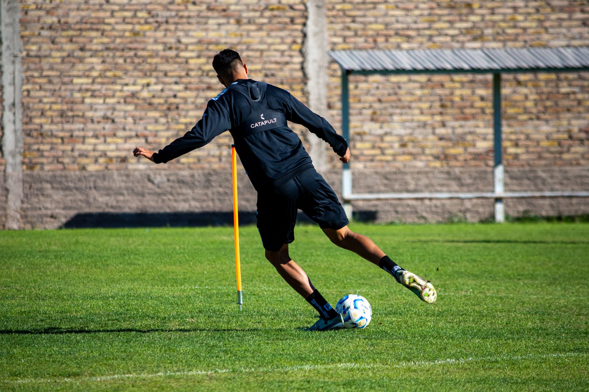 A footballer in full motion practicing agility drills on a sunny day