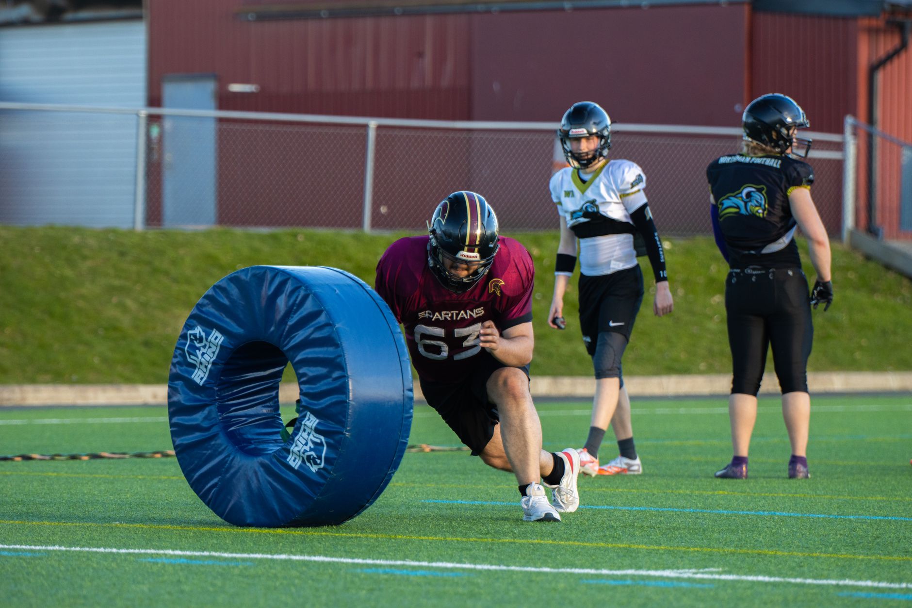 Action shot of football players practicing with tackling dummies on a field