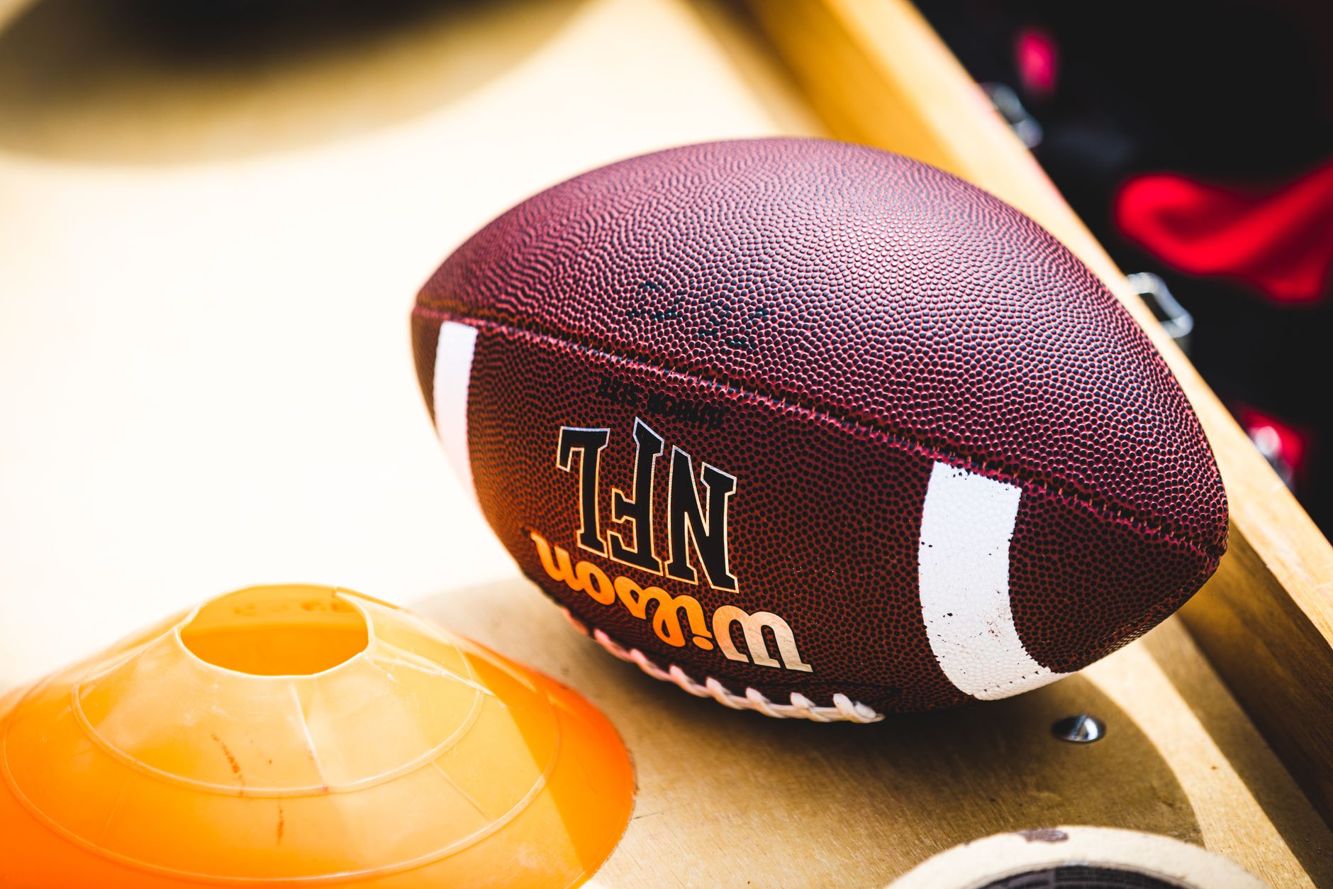 An American football placed on a training bench next to an orange