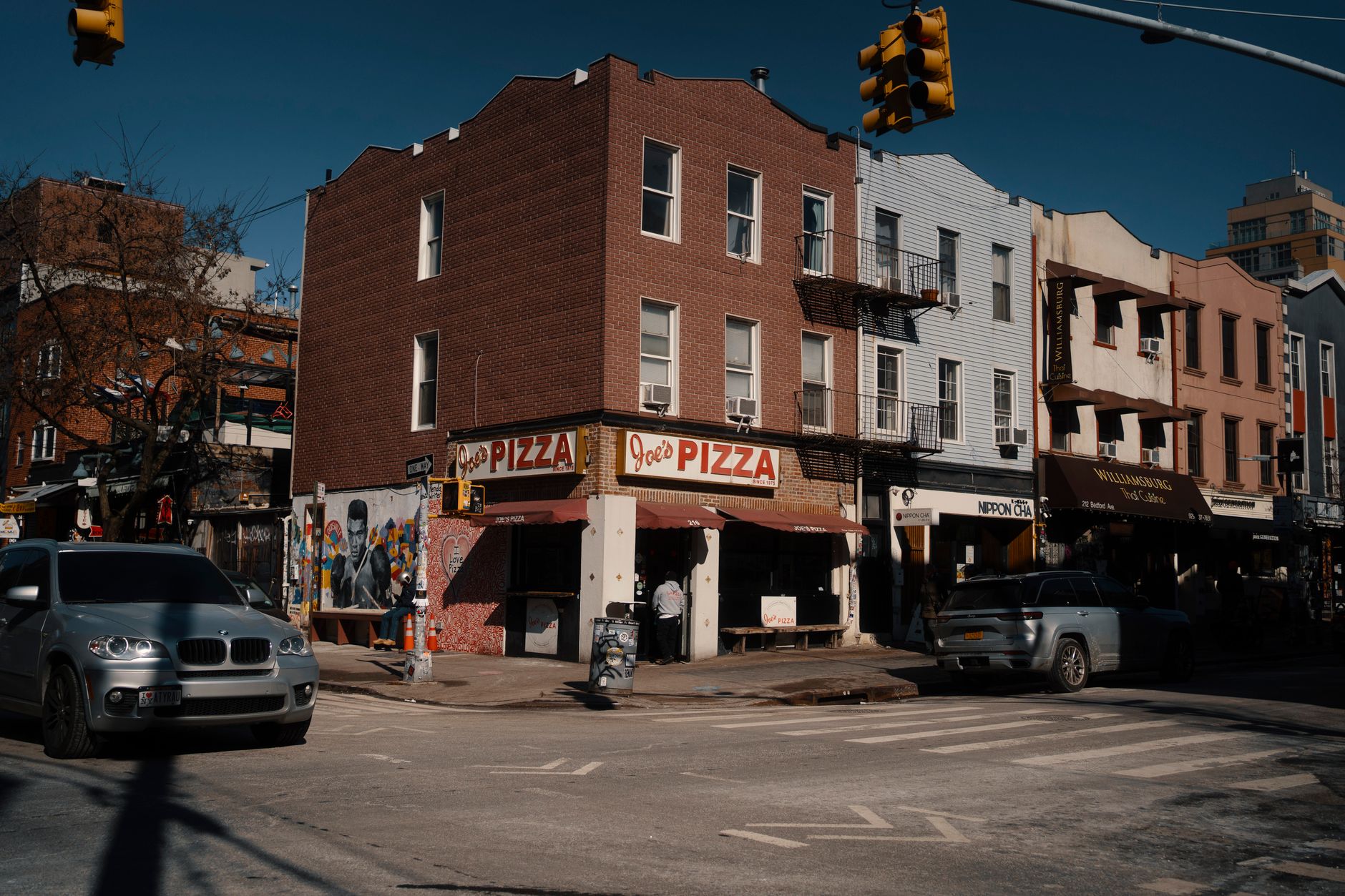 Street view of Joe's Pizza on a sunny day in Brooklyn, showcasing