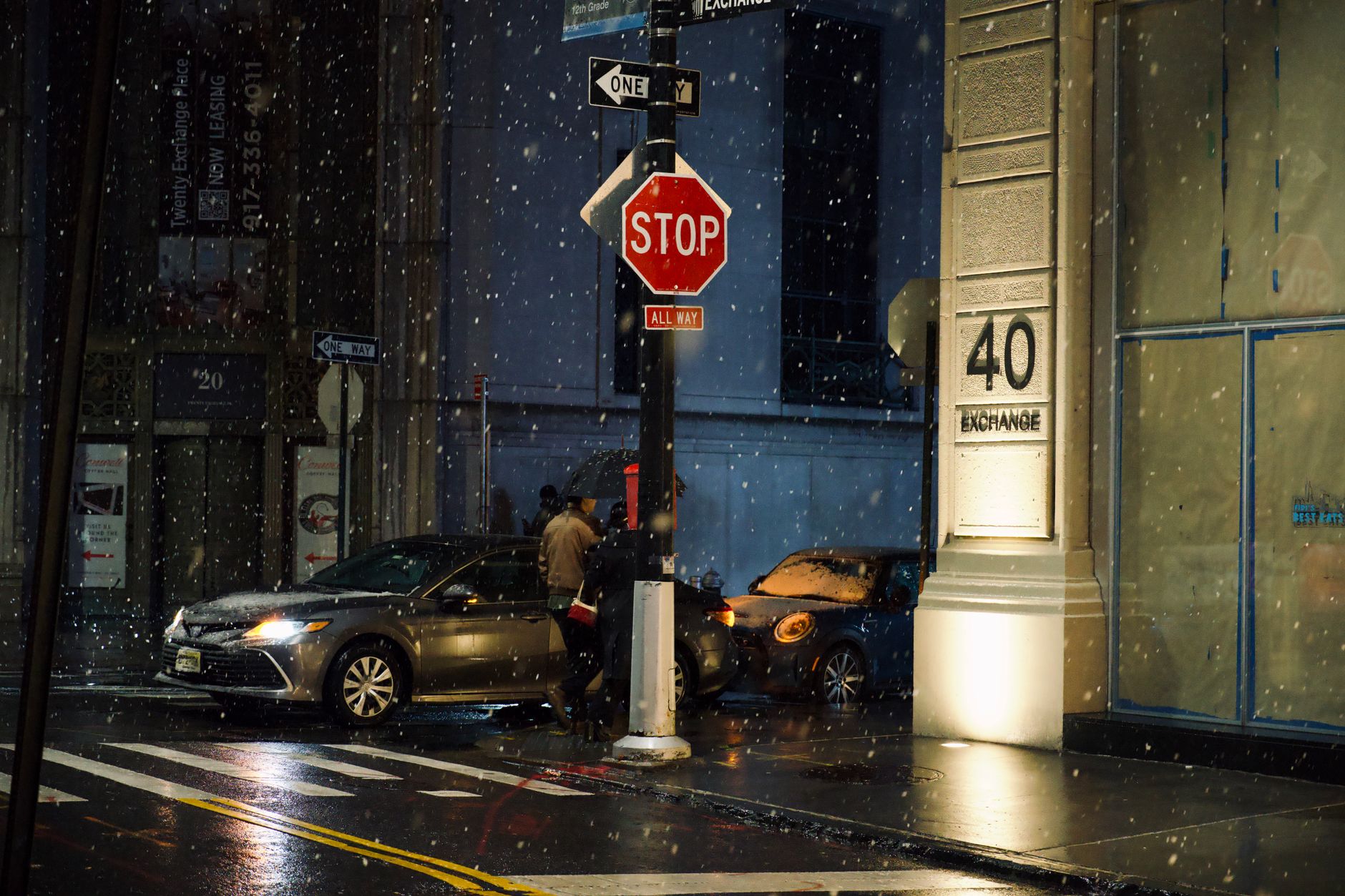 Snow falls on a city street corner in New York City at