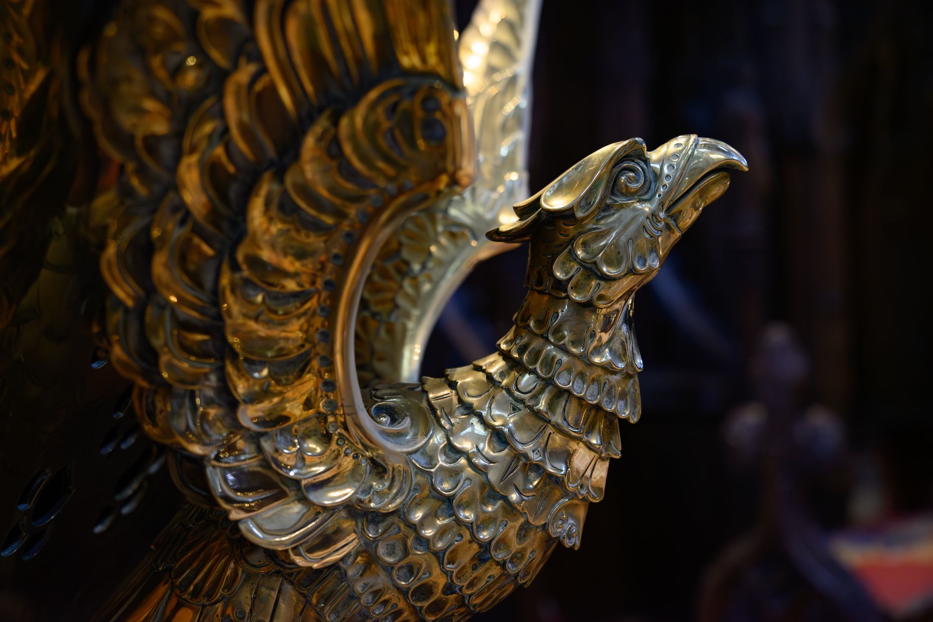 Detailed close-up of an ornate brass eagle sculpture with intricate feather design,