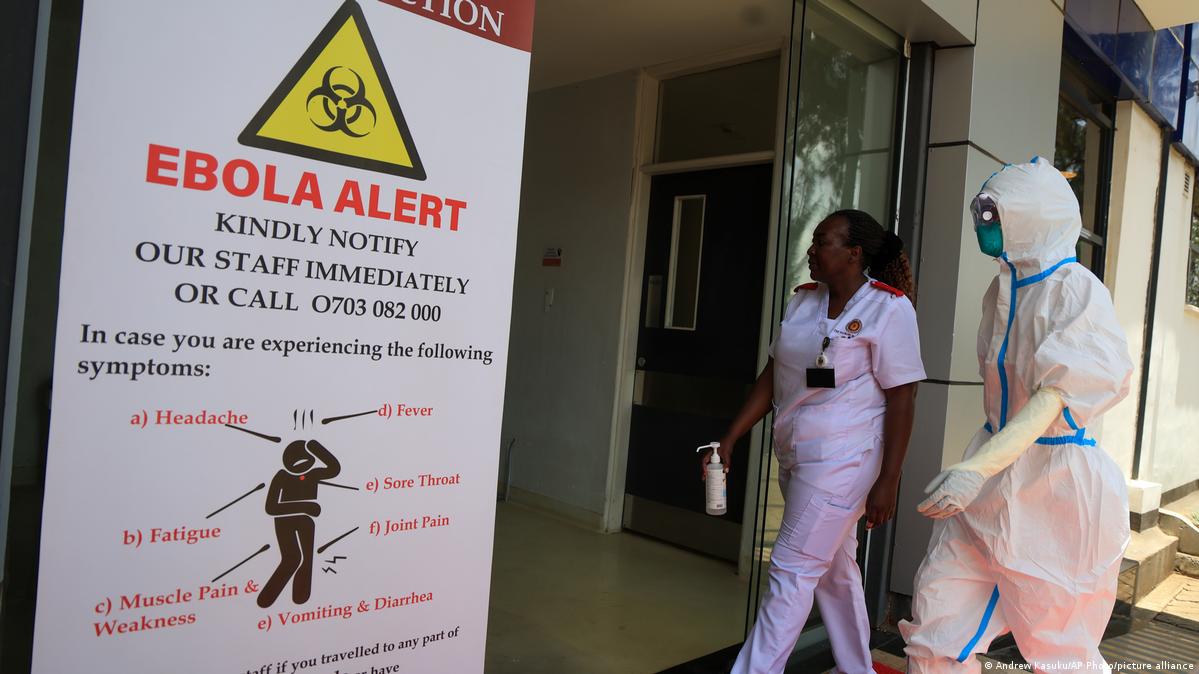 Health workers and officials walk outside a Ebola isolation facility at The