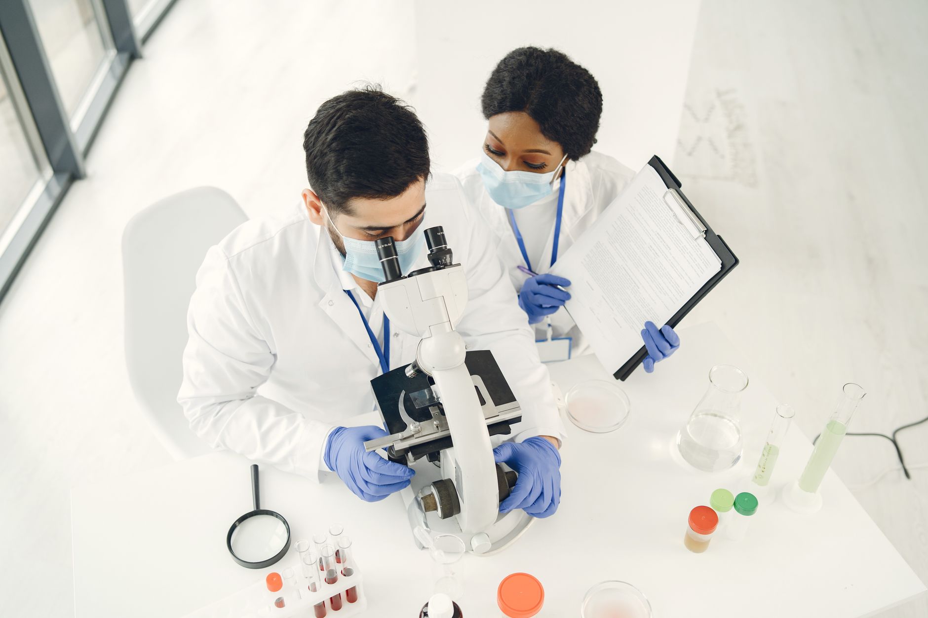 Two scientists examining samples under a microscope, showcasing teamwork in a lab