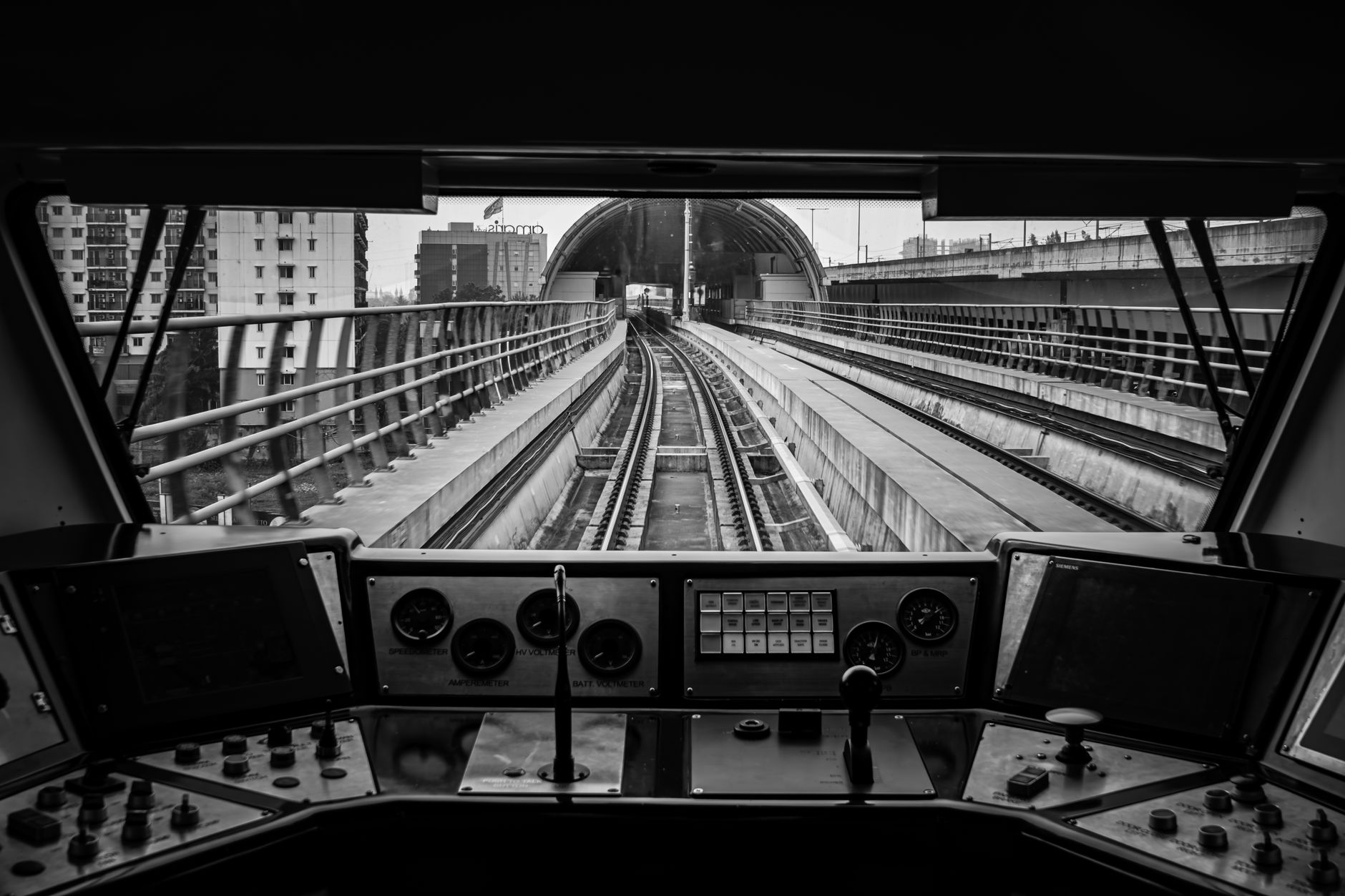 Monochrome shot from inside a train cockpit showing tracks and gauges.