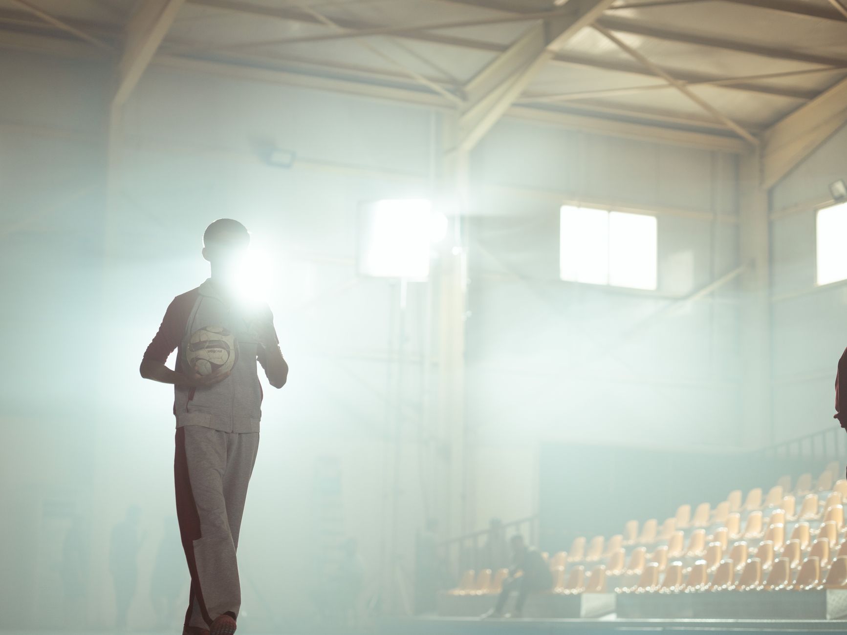 A silhouette of a basketball player holding a ball in a sunlit
