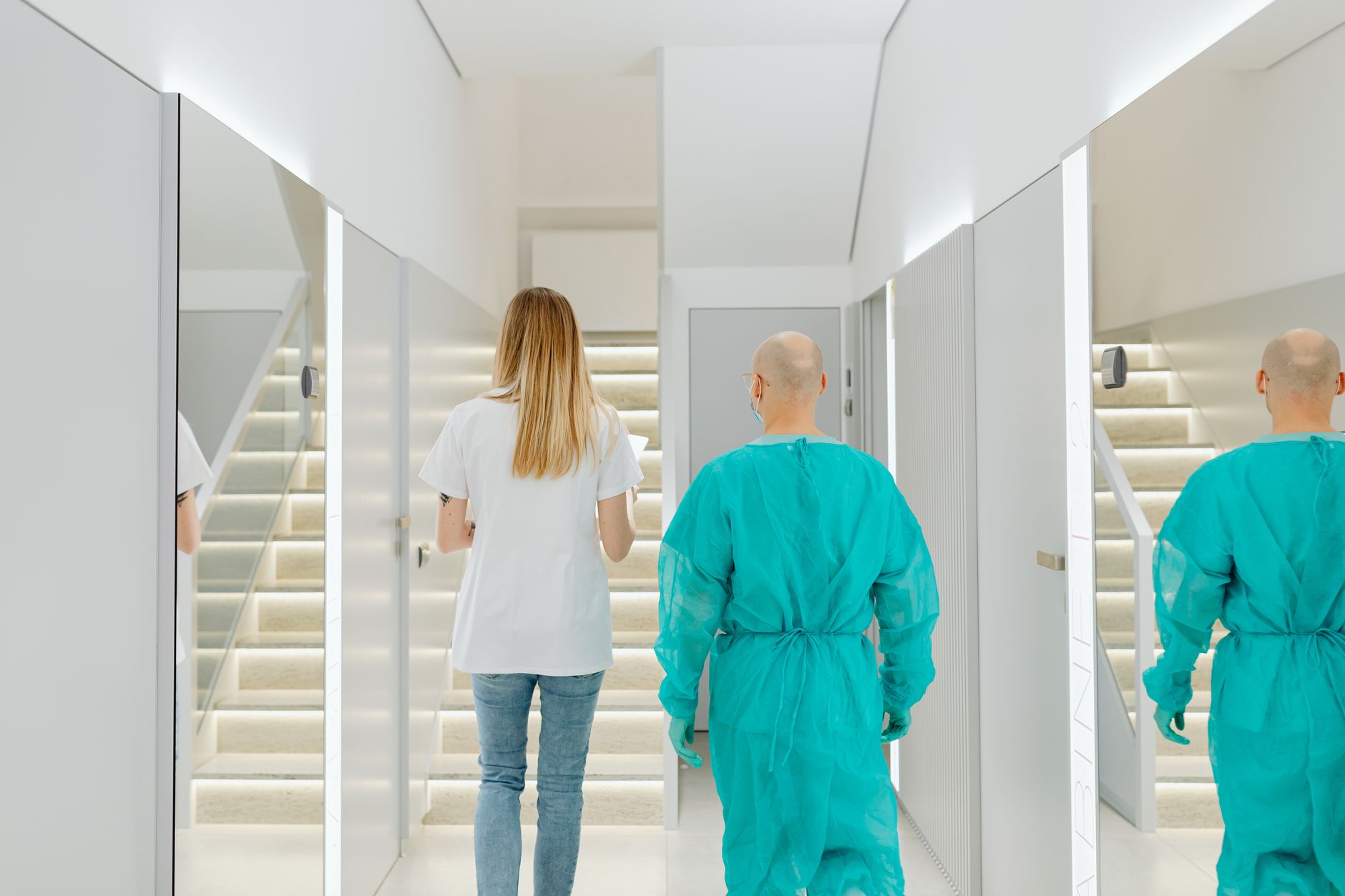 Two medical practitioners walking down a bright clinic hallway with reflections in