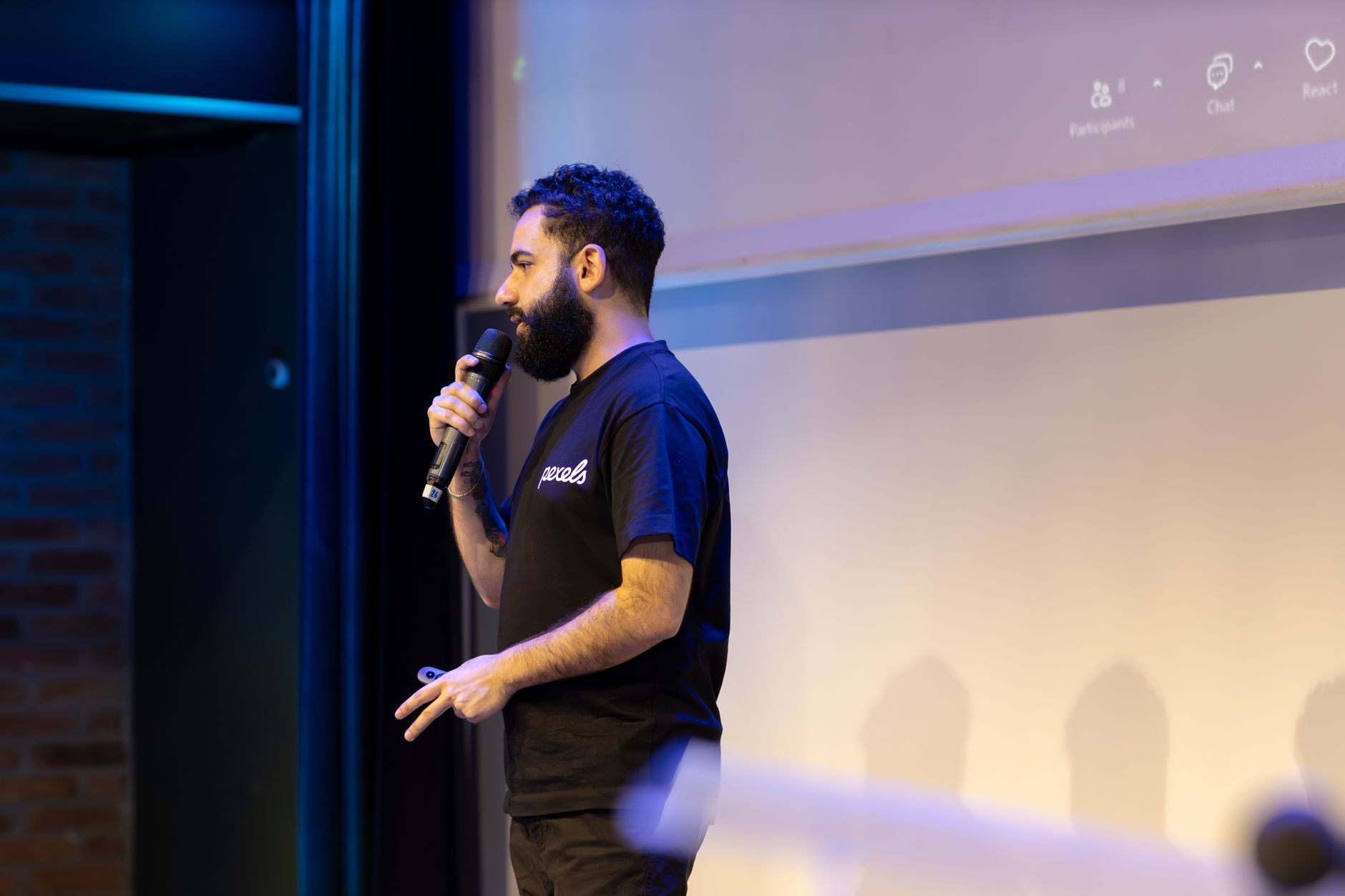 Man speaking into microphone during a presentation indoors.