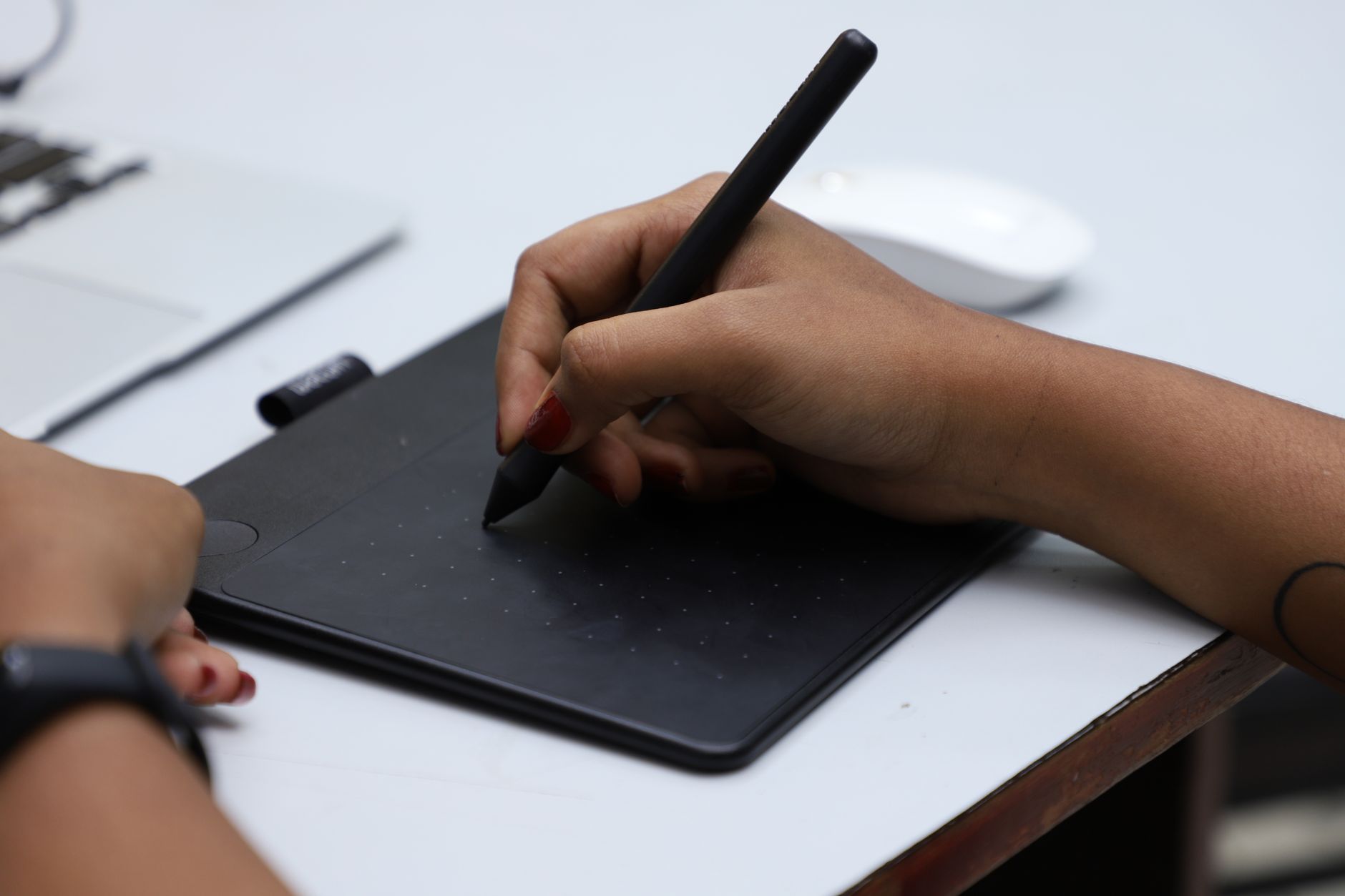 Close-up of hands using a graphic tablet with stylus for creative design,
